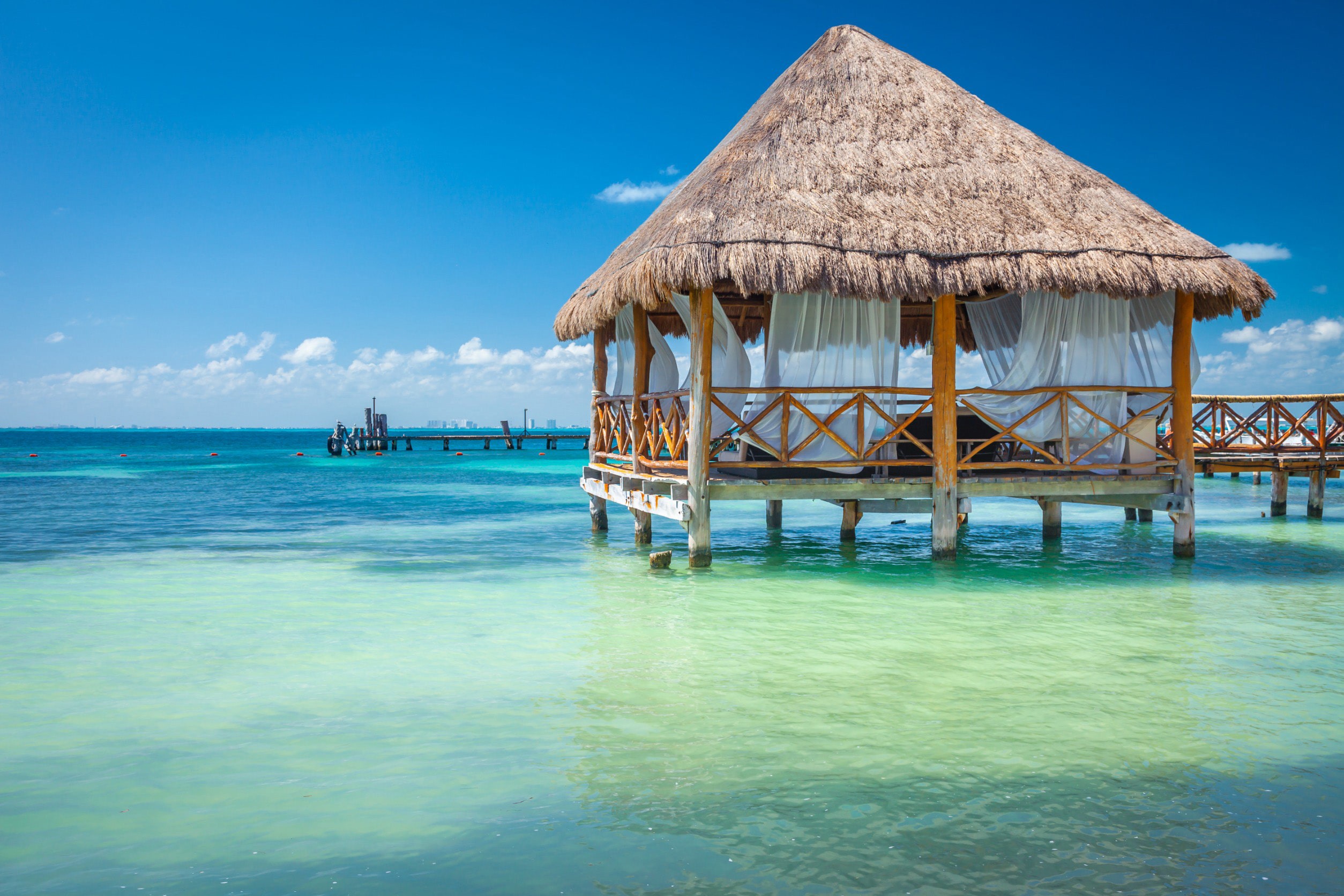 En bungalow står i vackert turkosblått vatten med blå himmel i Cancun, Mexiko