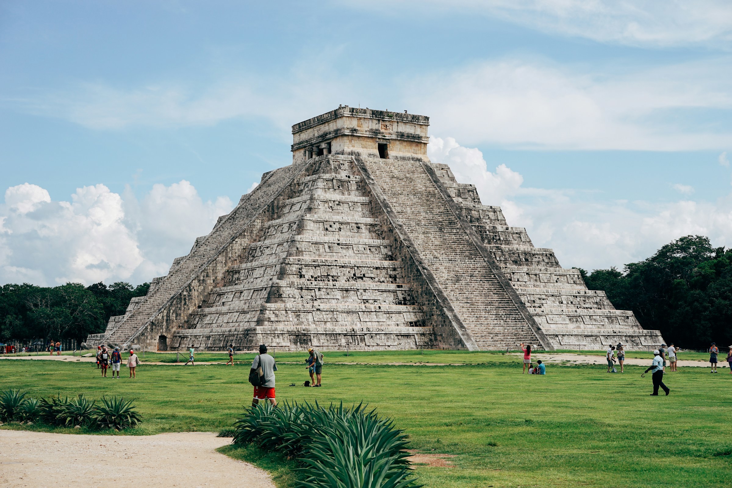 Bild på Pyramiden i Chichen Itza i Mexiko med grönt gräs omkring sig och blå himmel bakomsig