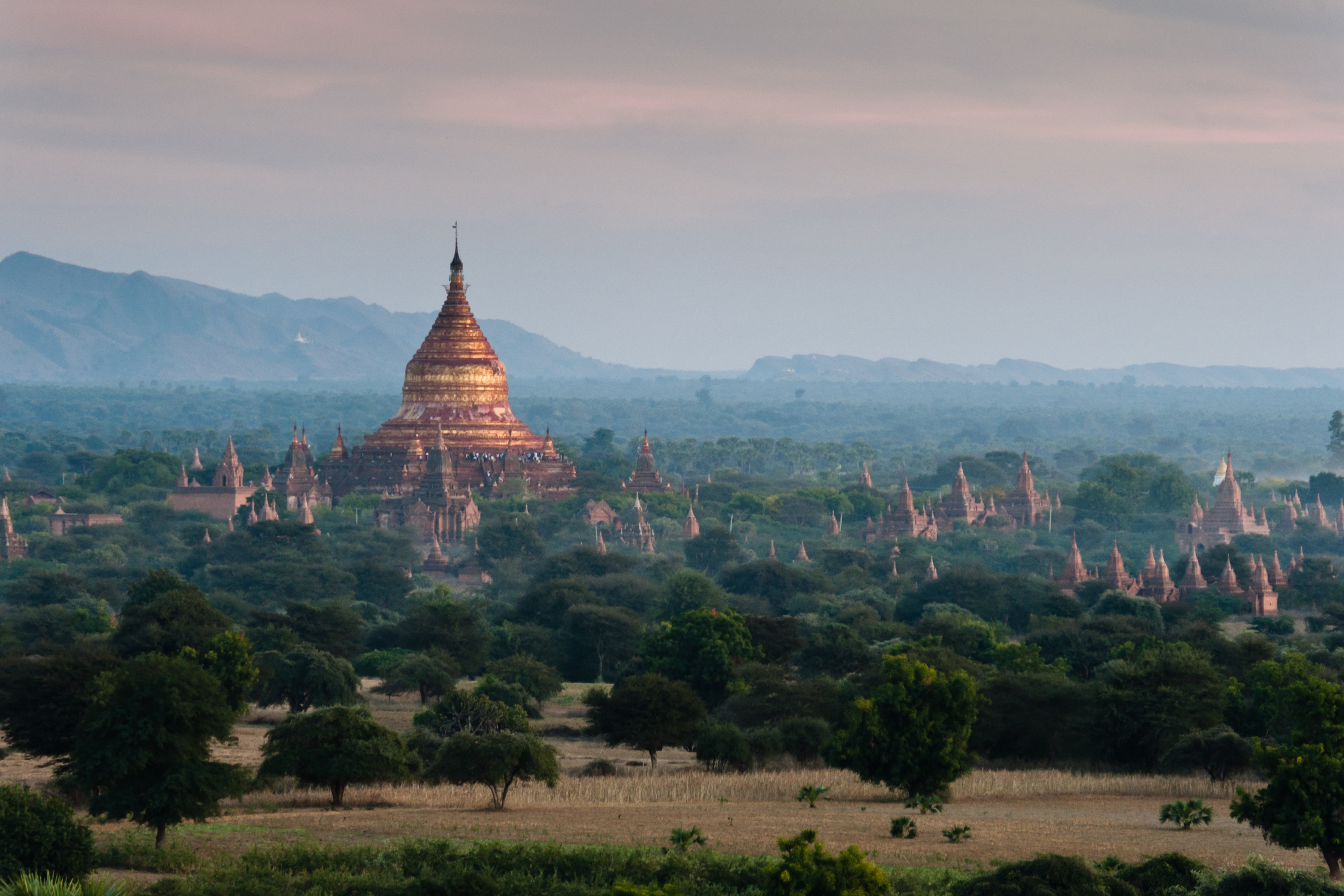 Travel to Myanmar - Beautiful jungle around an Asian temple during a sunset with faint fog and cliffs in the background