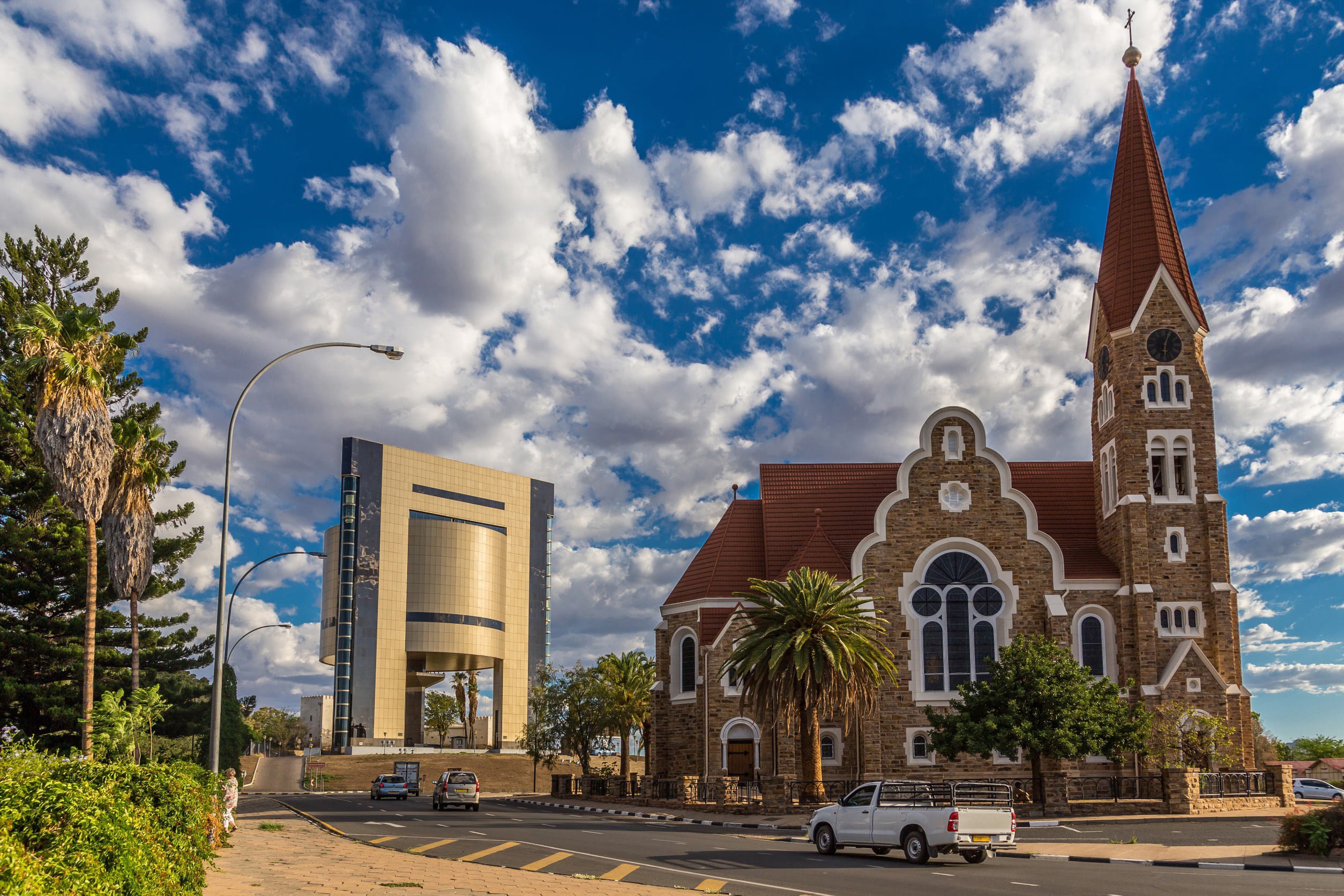 Beautiful brick church in Windhoek with greenery around it and blue sky with clouds in the background