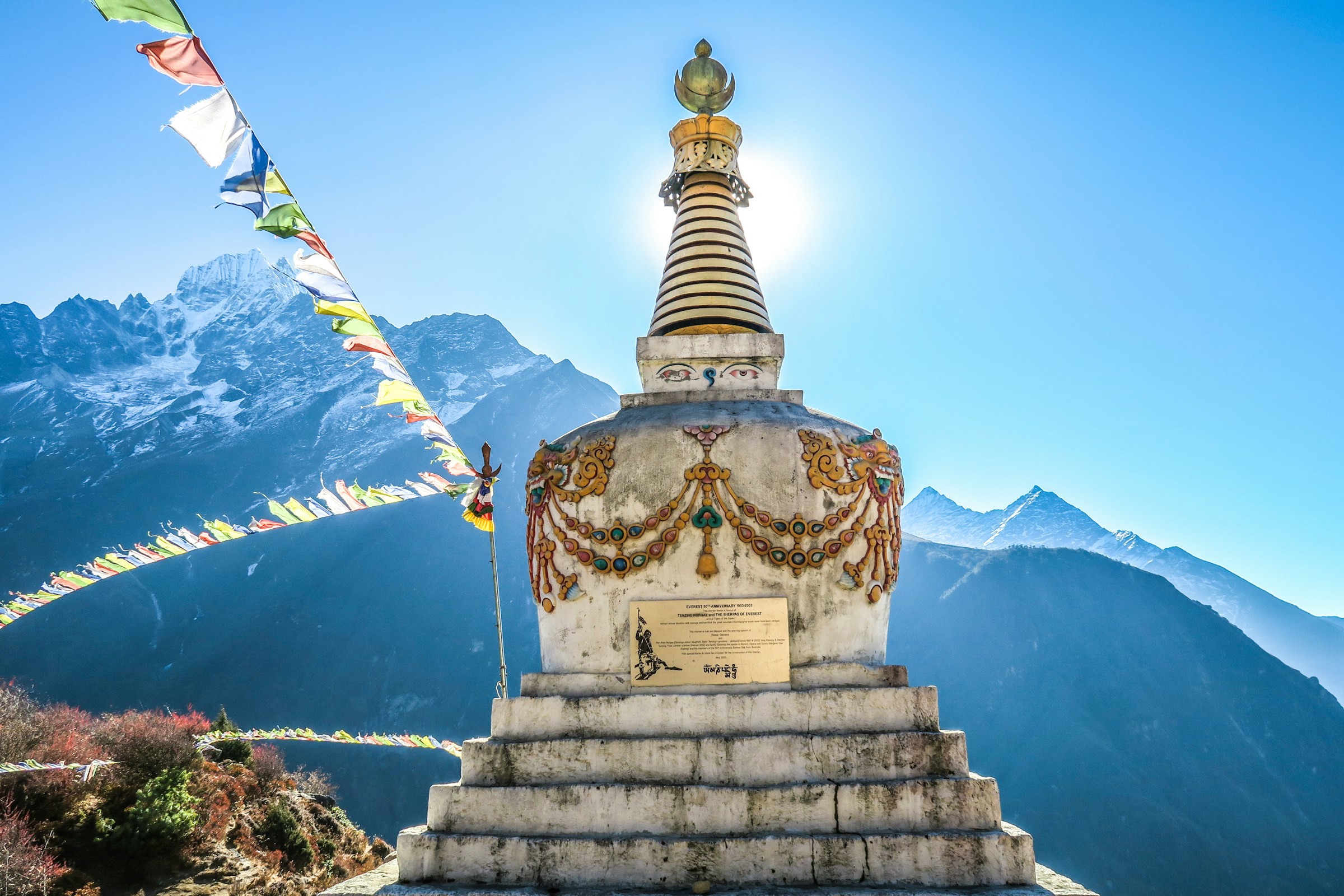 Staty i Himalaya bergen ned vackra berg i bakgrunden, blå himmel och flaggor som viftar i vinden