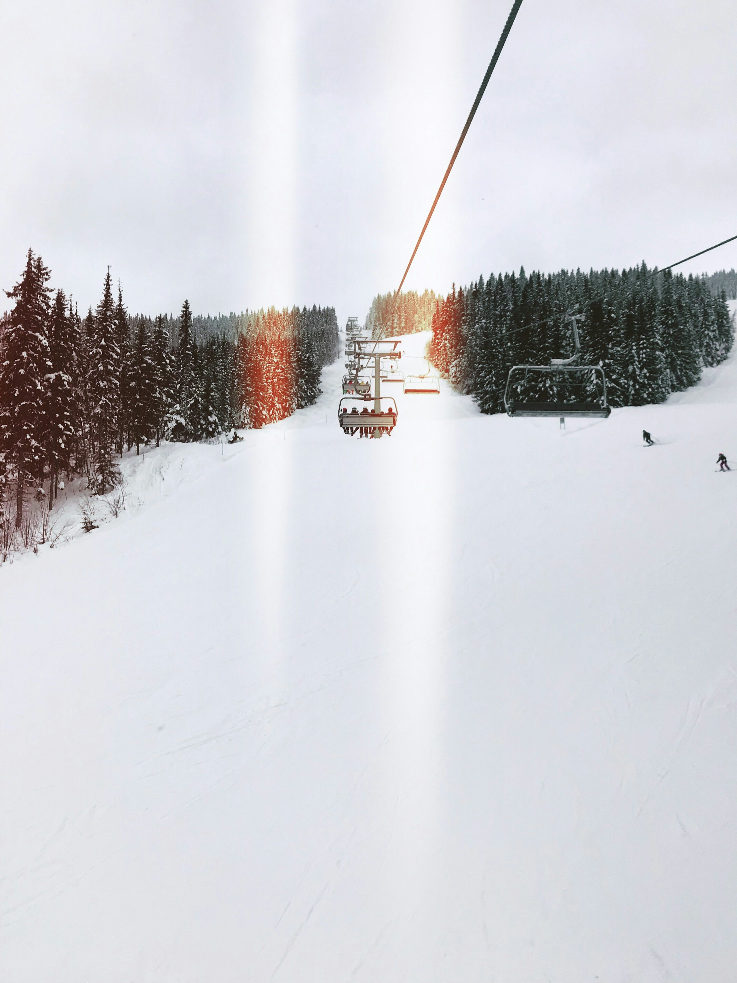 Två personer åker i en skidlift över en snötäckt skidbana i Trysil, Norge