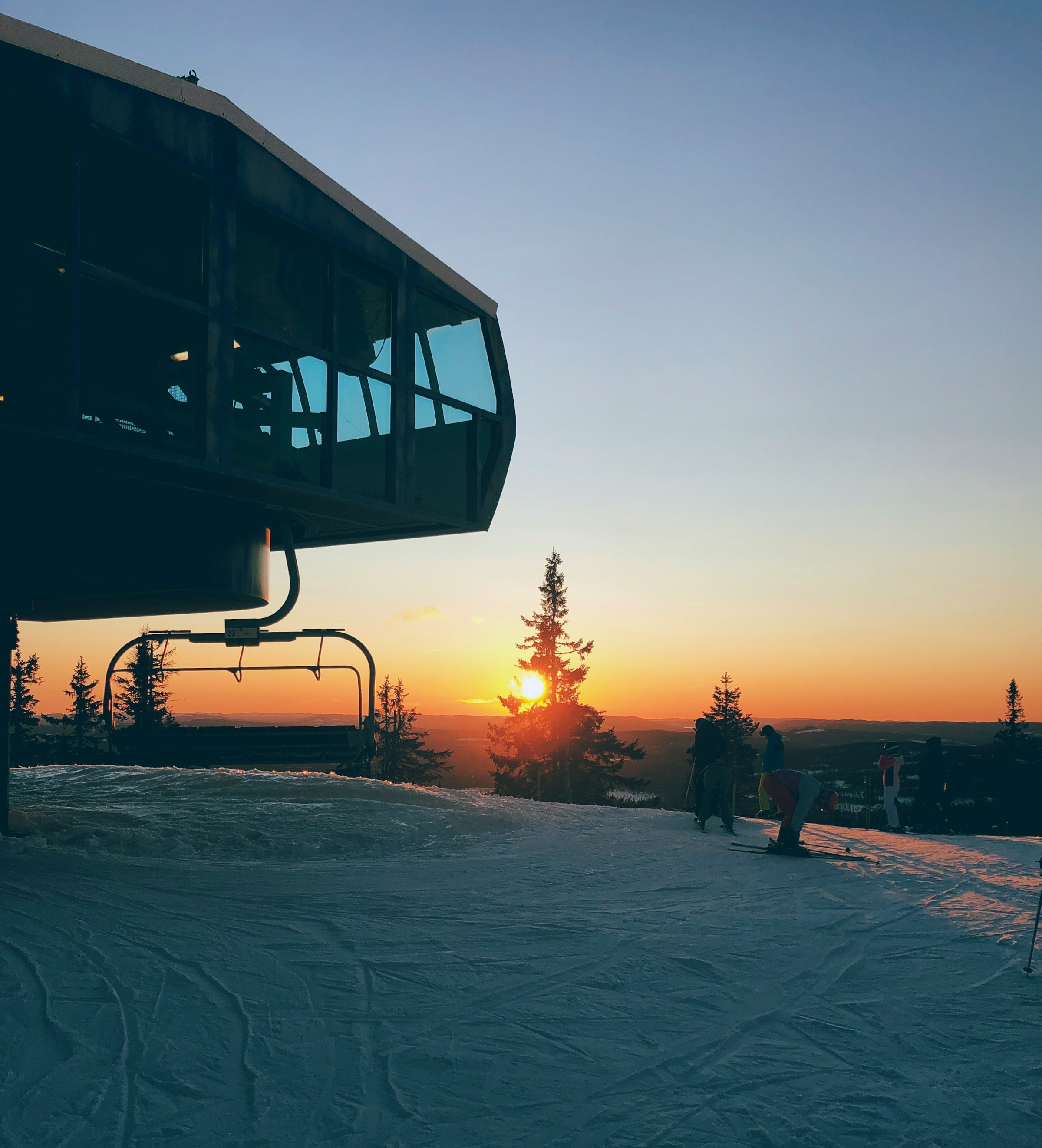 Solnedgång över snötäckt landskap i Trysil med skidlift och träd till vänter sida.