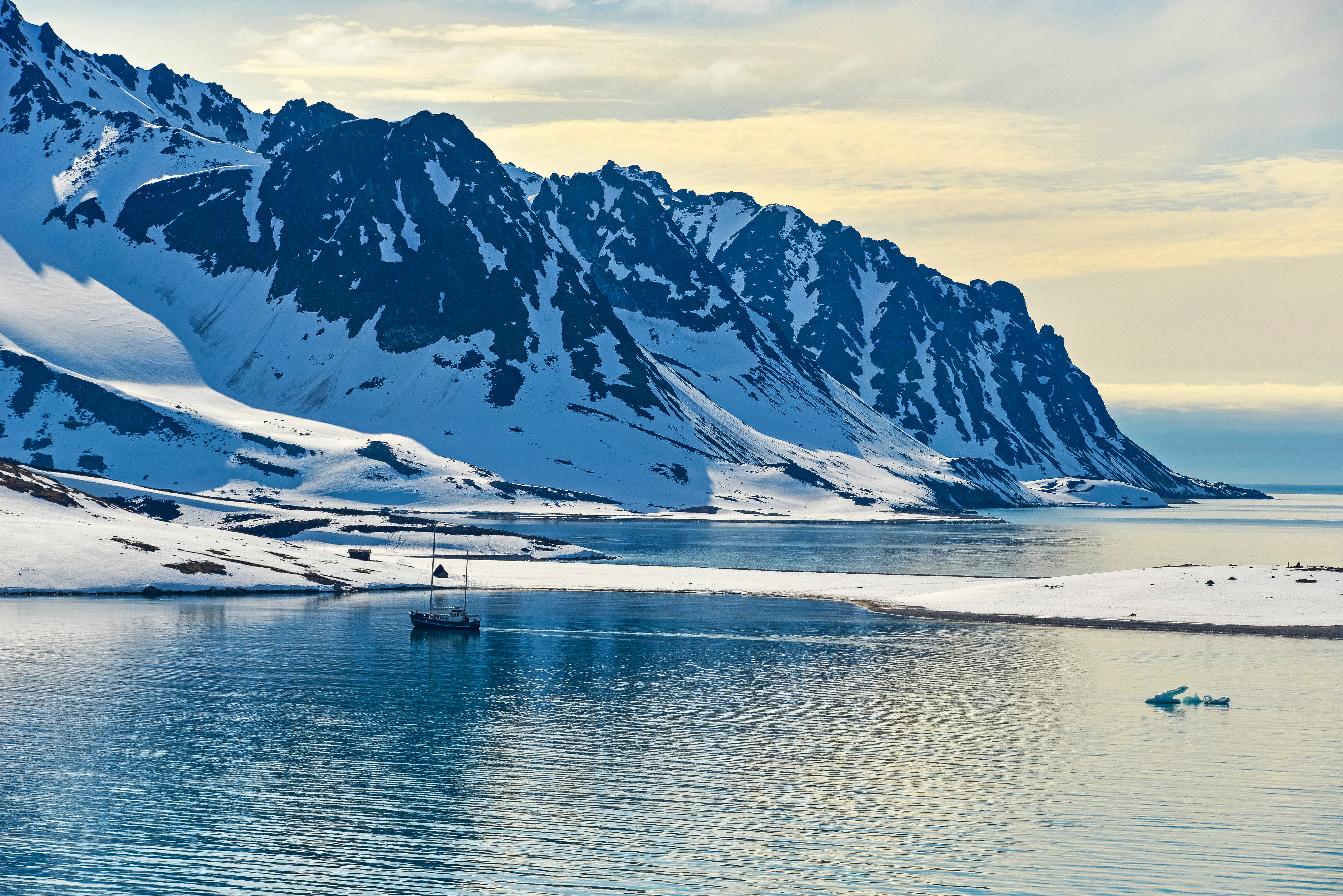 Snow-capped mountains down to ice water at early sunset in Svalbard