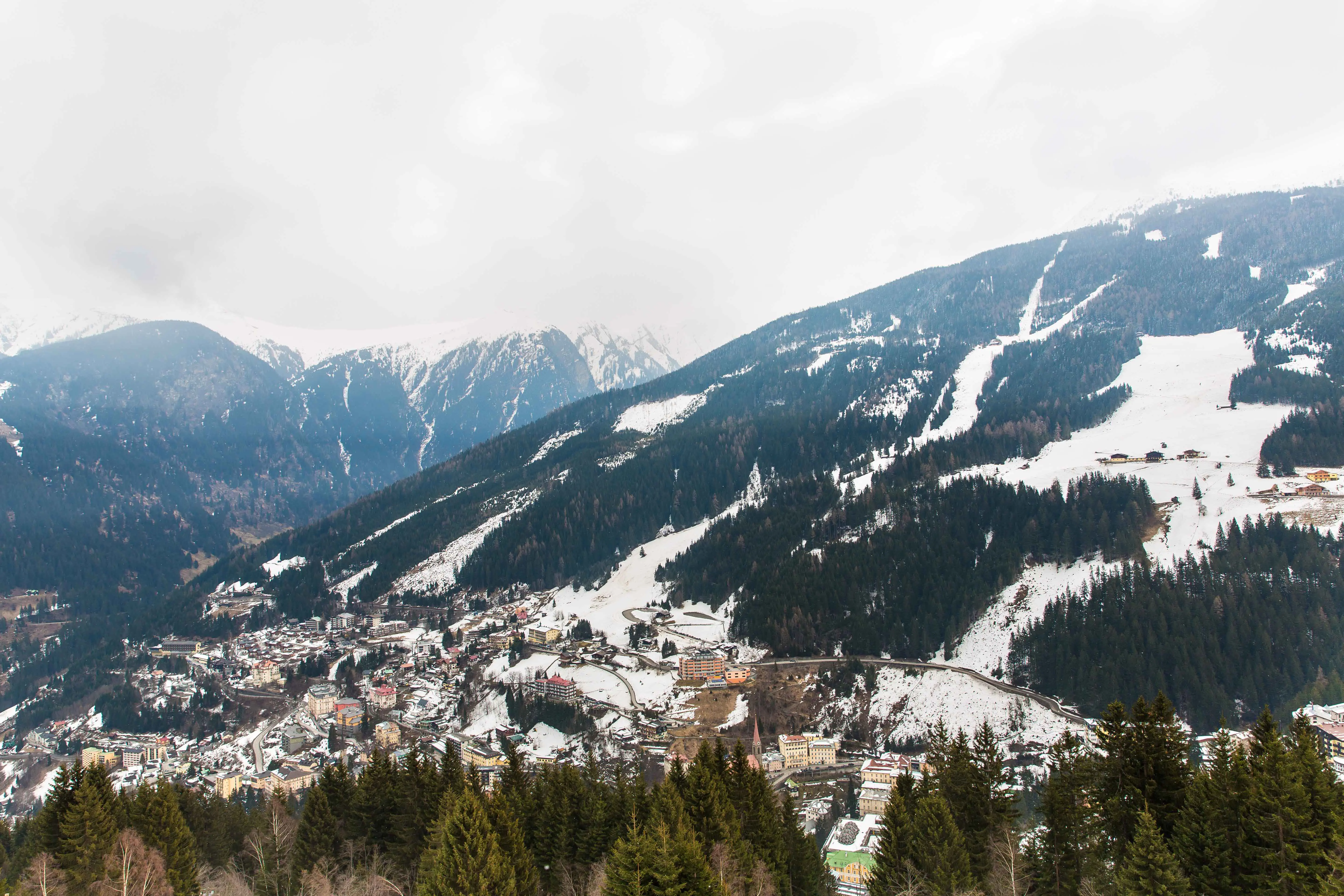 Travel to Bad Gastein - Bird's-eye view of ski resort and buildings between snow-capped mountains and wilderness in Bad Gastein