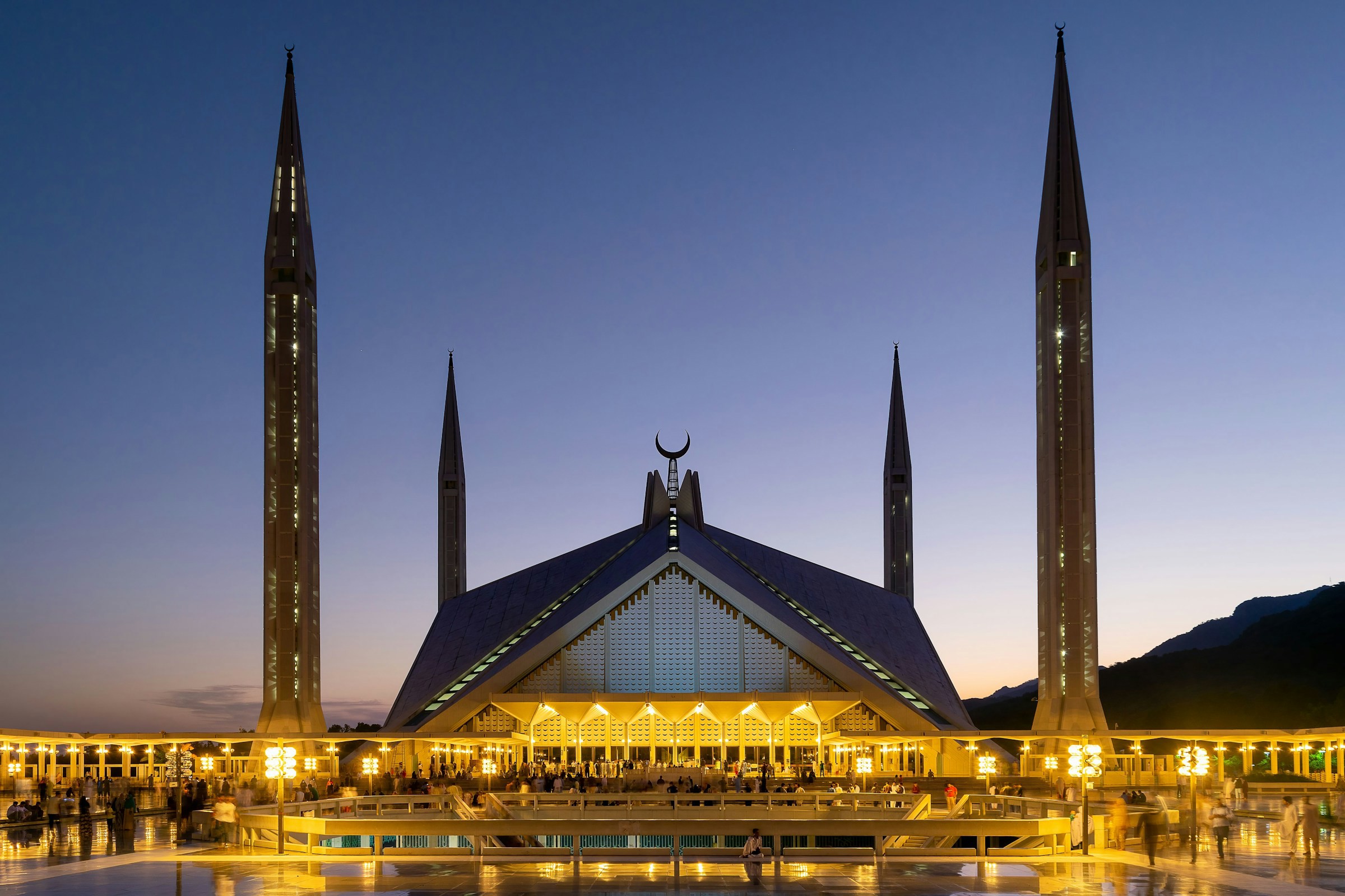 Vacker moské på ett torg i Pakistan under skymning med torn som stäcker sig upp mot en lila himmel