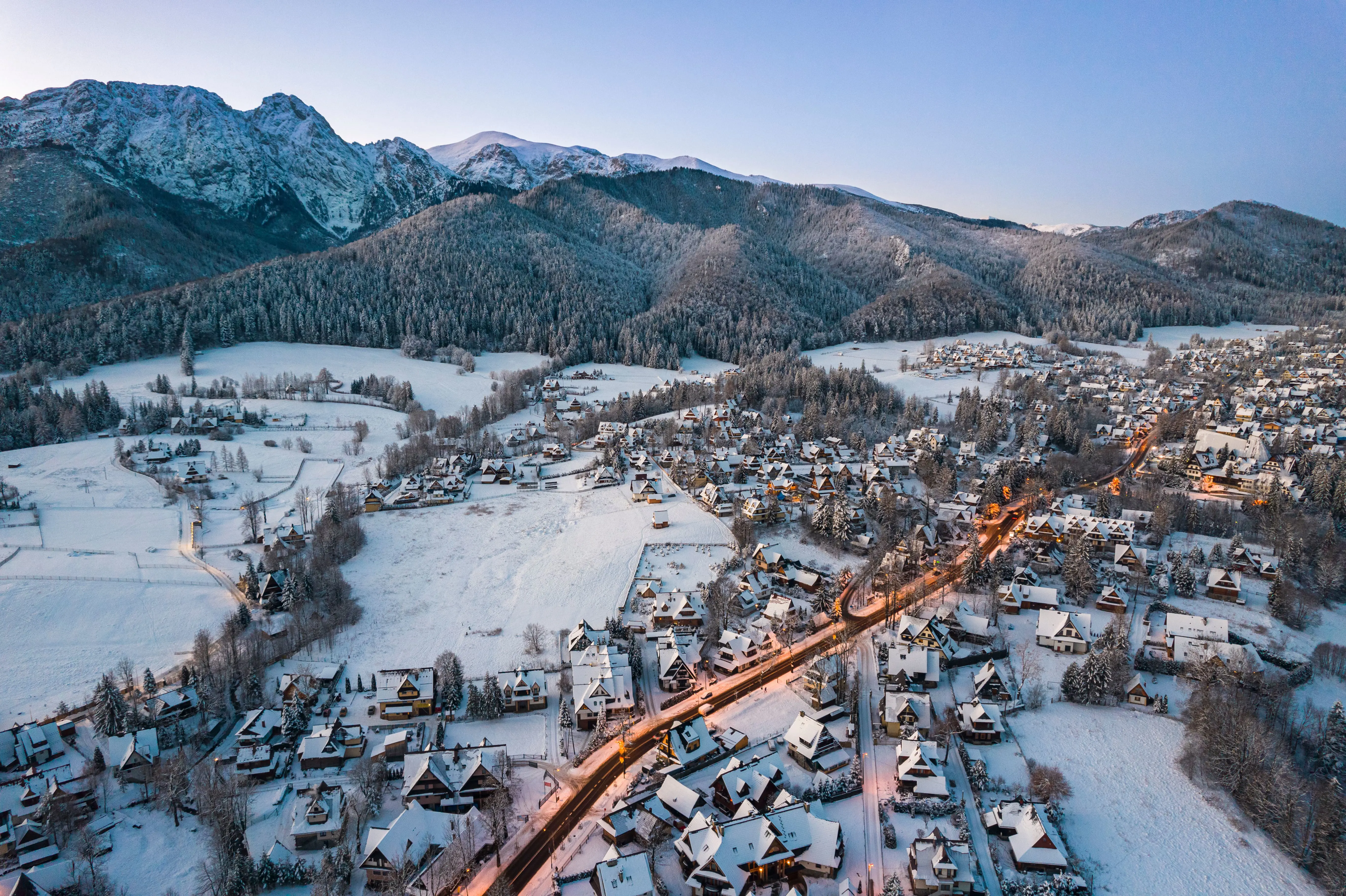 Travel to Zakopane - Panoramic view of snow-covered city in a valley during a sunset with mountains in the background