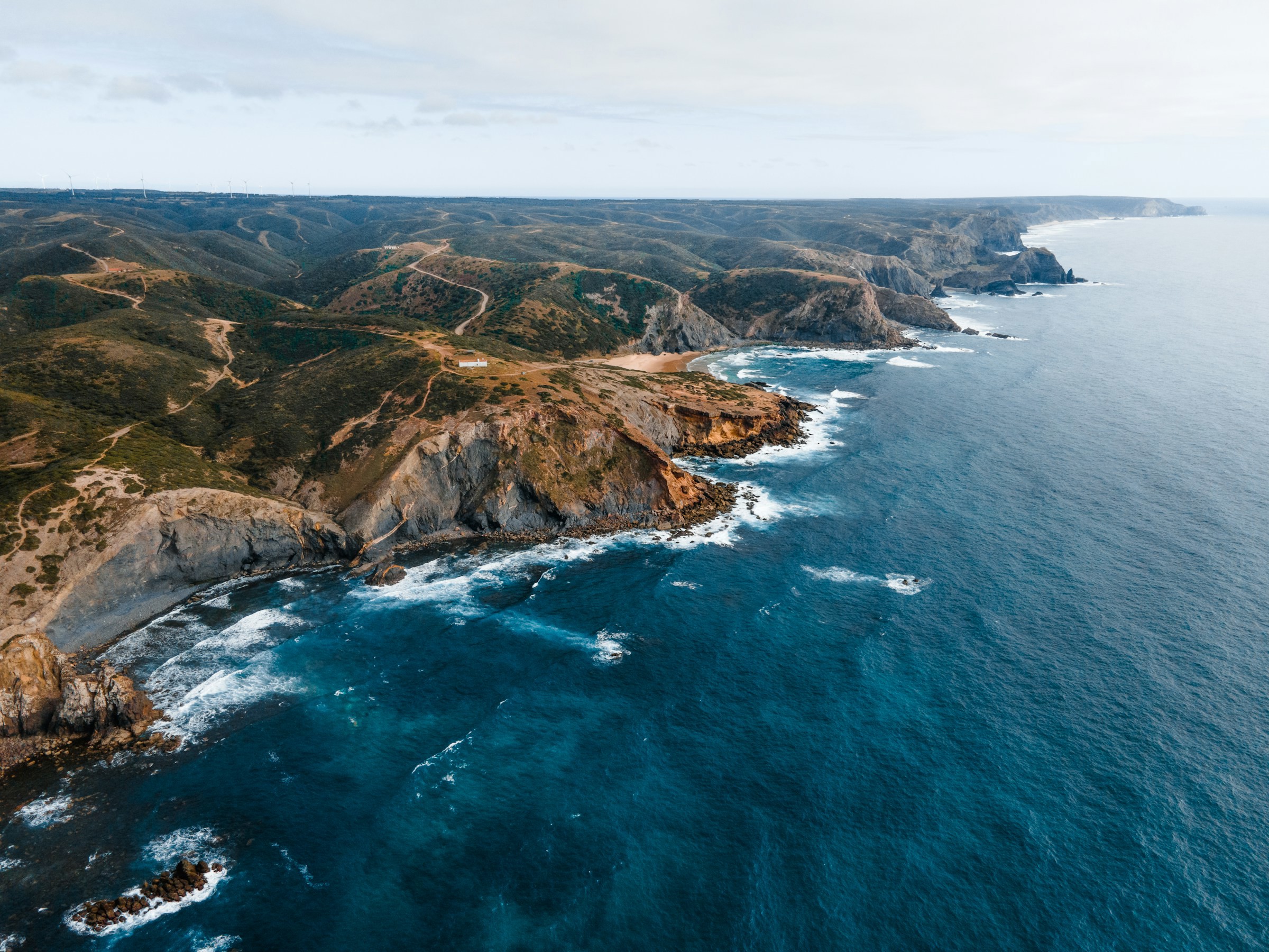 Fågelvy över kusten i Portugal där havet möter stora klippor med skog omkring sig