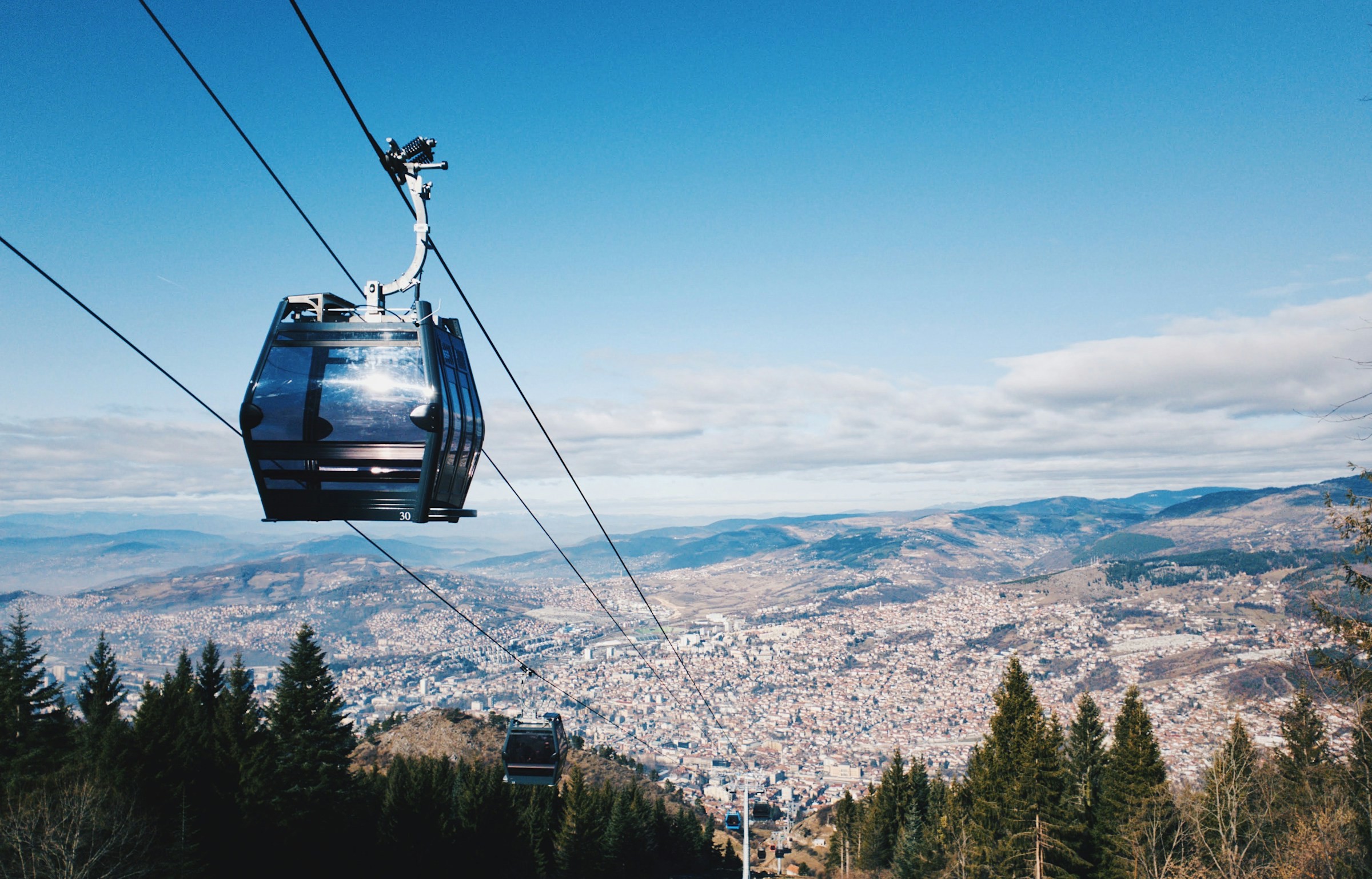 Linbana över Sarajevo med utsikt över stadslandskap och skog i förgrunden.