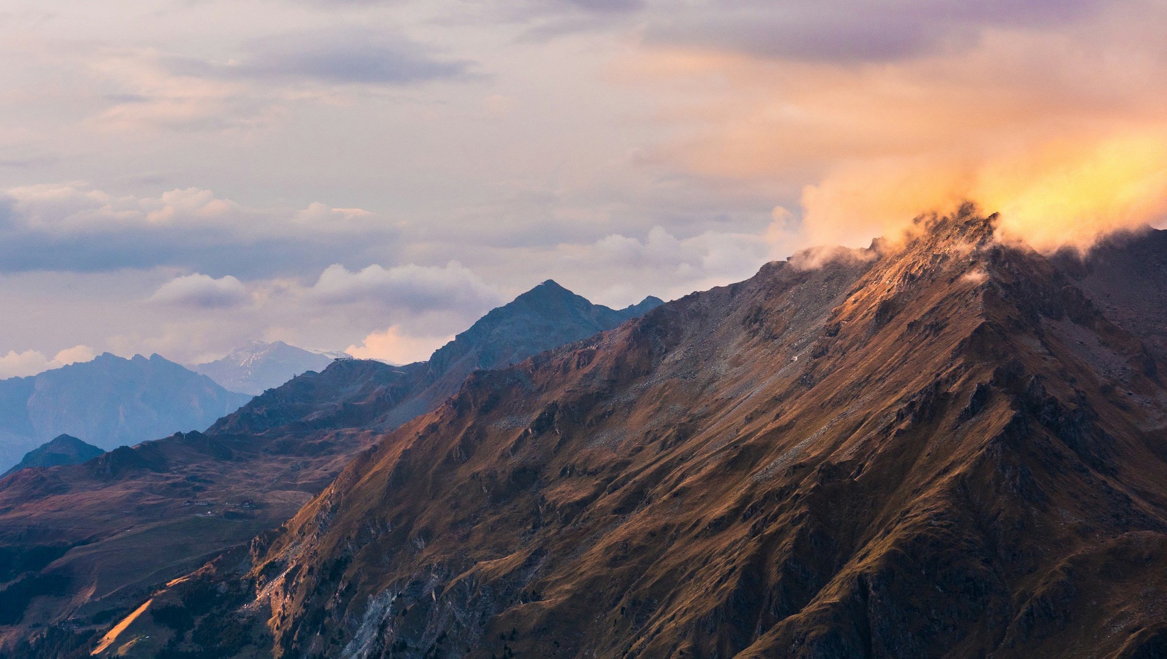 Bergslandskap vid solnedgång med dramatiskt ljus och moln över bergstopparna i Verbier.