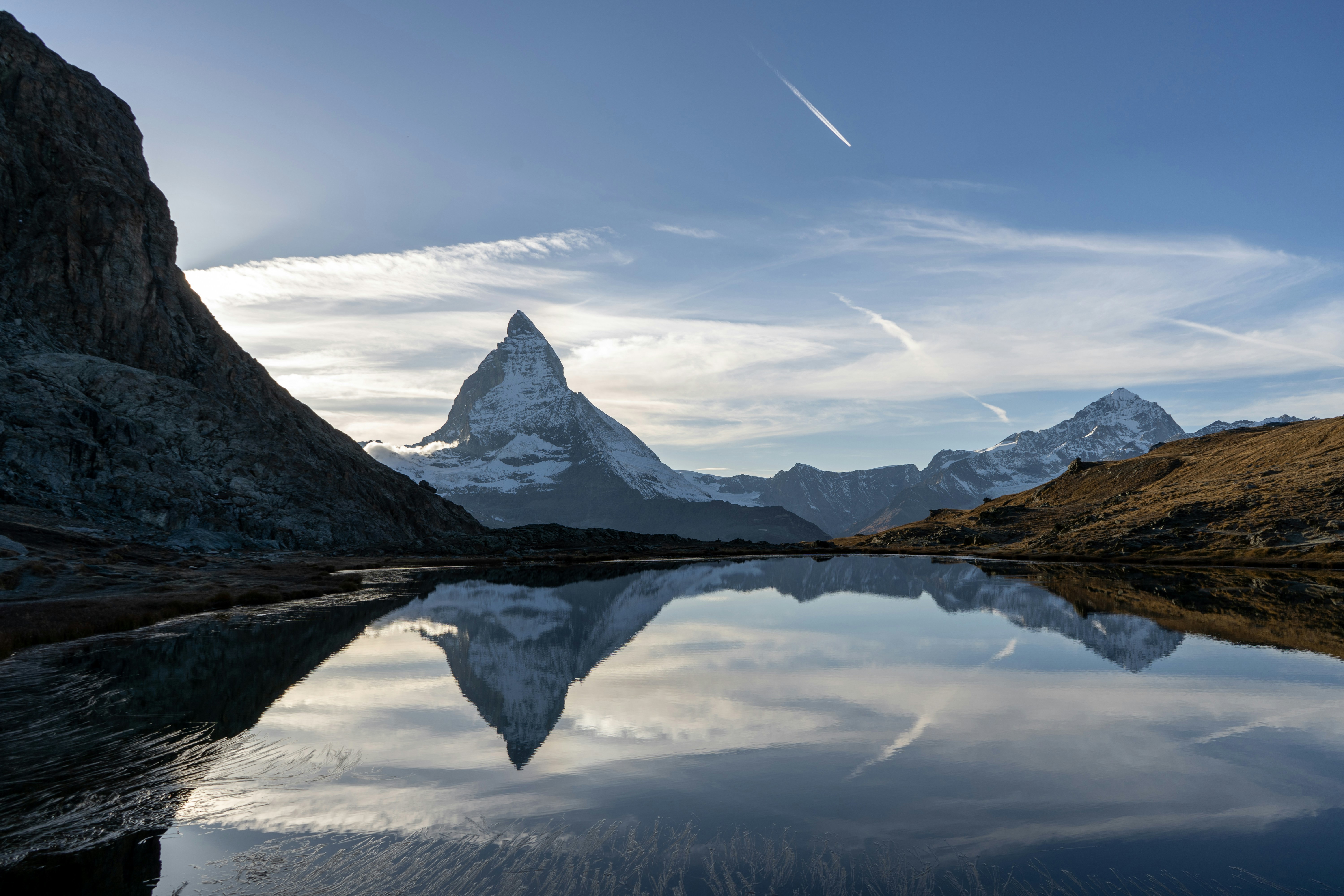 En stillsam sjö med vackra vinterberg i bakgrunden under en tidig kväll i Schweiz