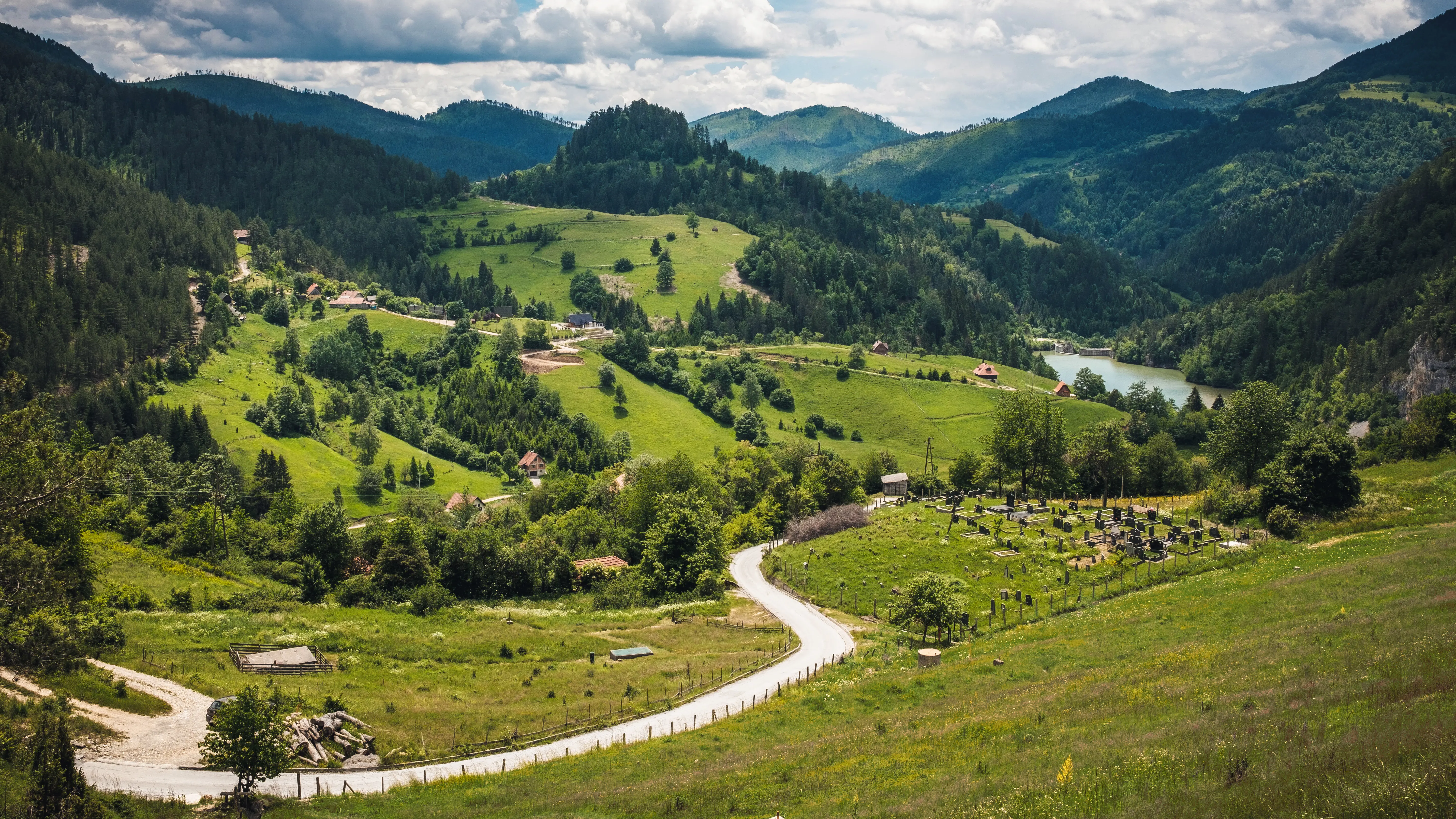 Resa till Serbien - Naturskönt landskap med slingrande väg genom gröna kullar, berg, skogar och en stilla sjö.