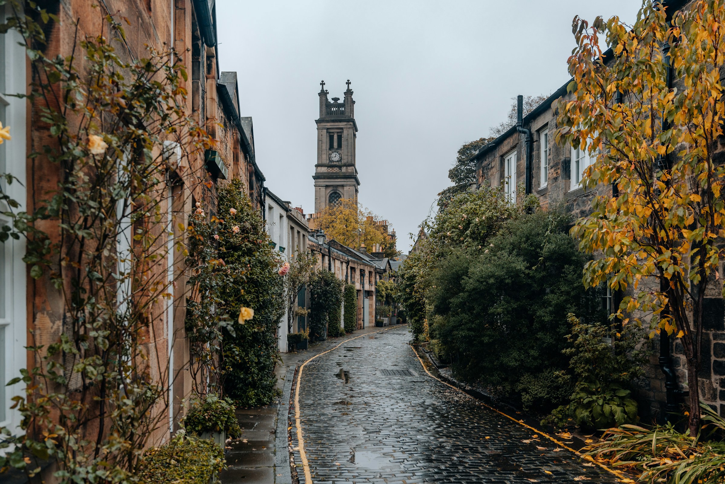 Vacker tom gata efter regn i Edinburgh, Skottland med ett kyrkotorn i bakgrunden