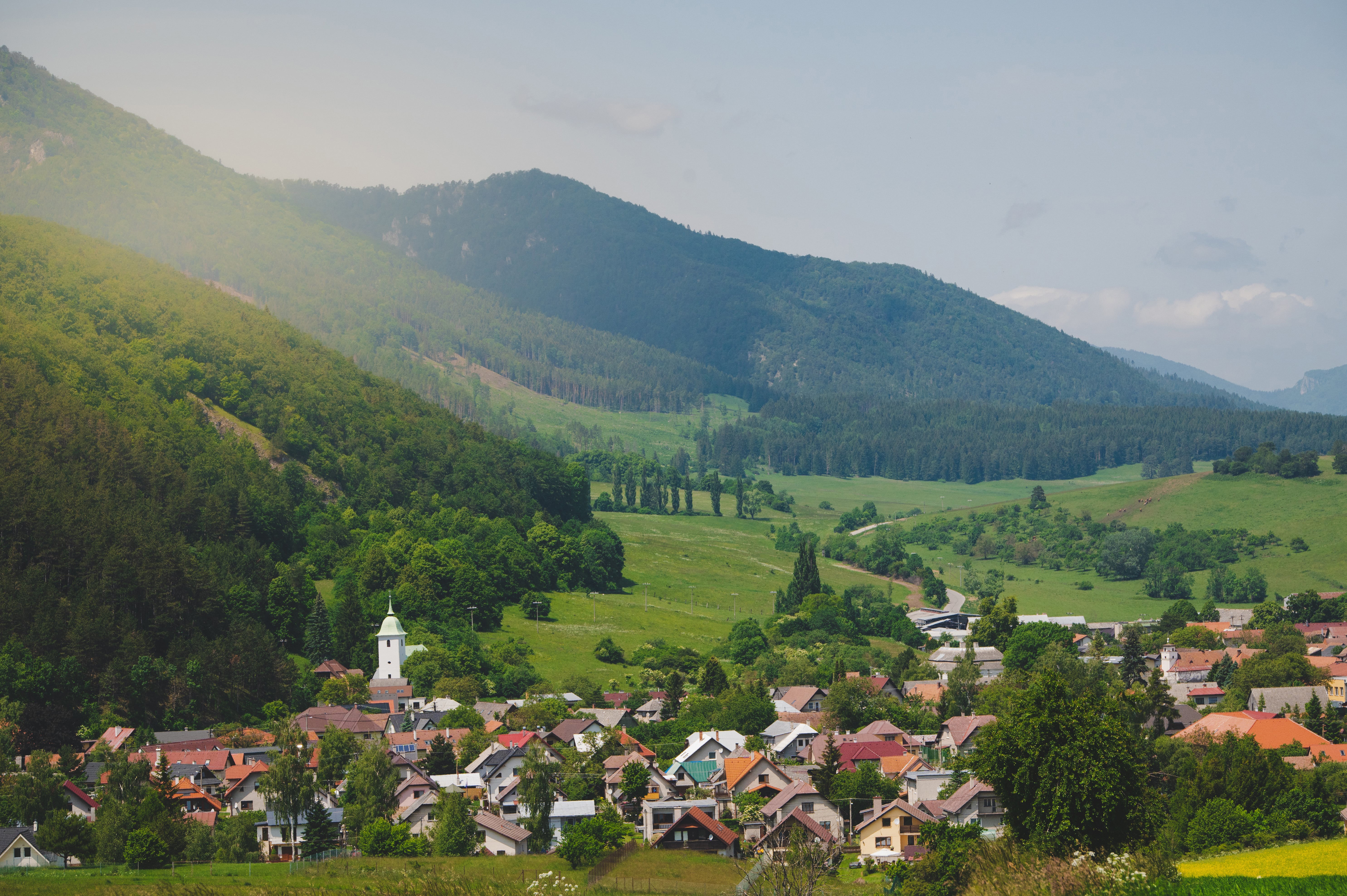 Utkant av stad i Slovakien med byggnader mot grönskande skog och berg med en soluppgång