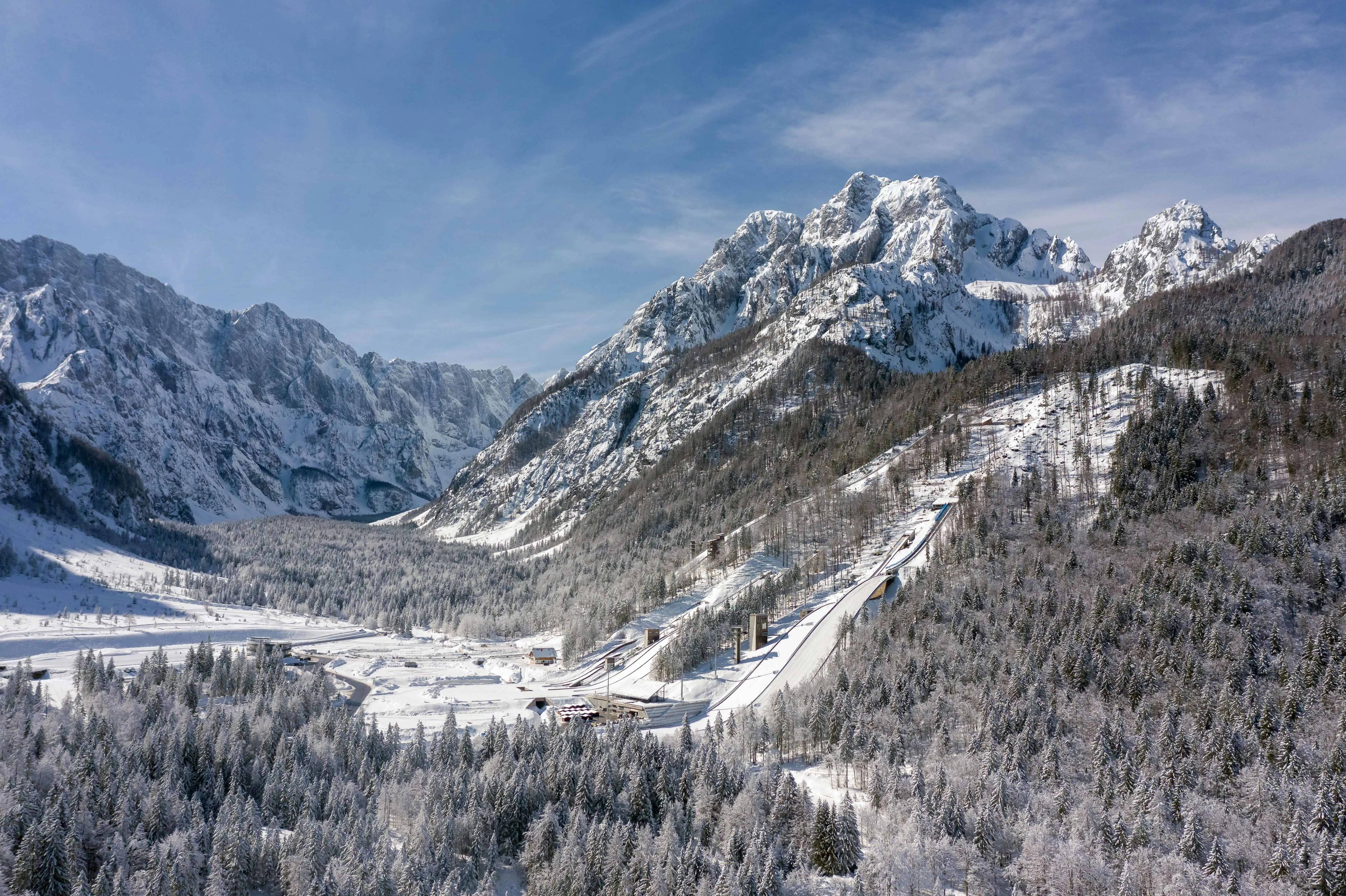 Vackert naturlandskap i Kranjska Gora, Slovenien med snötäckta berg och skidbacke ner i ett skidresort