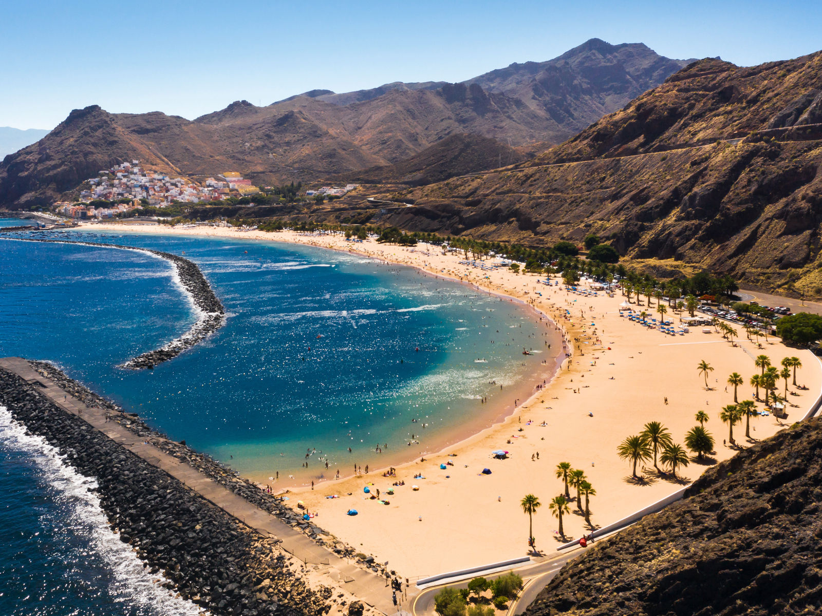 Resa till Kanarieöarna - strand med blått hav omgivet av berg och grönska