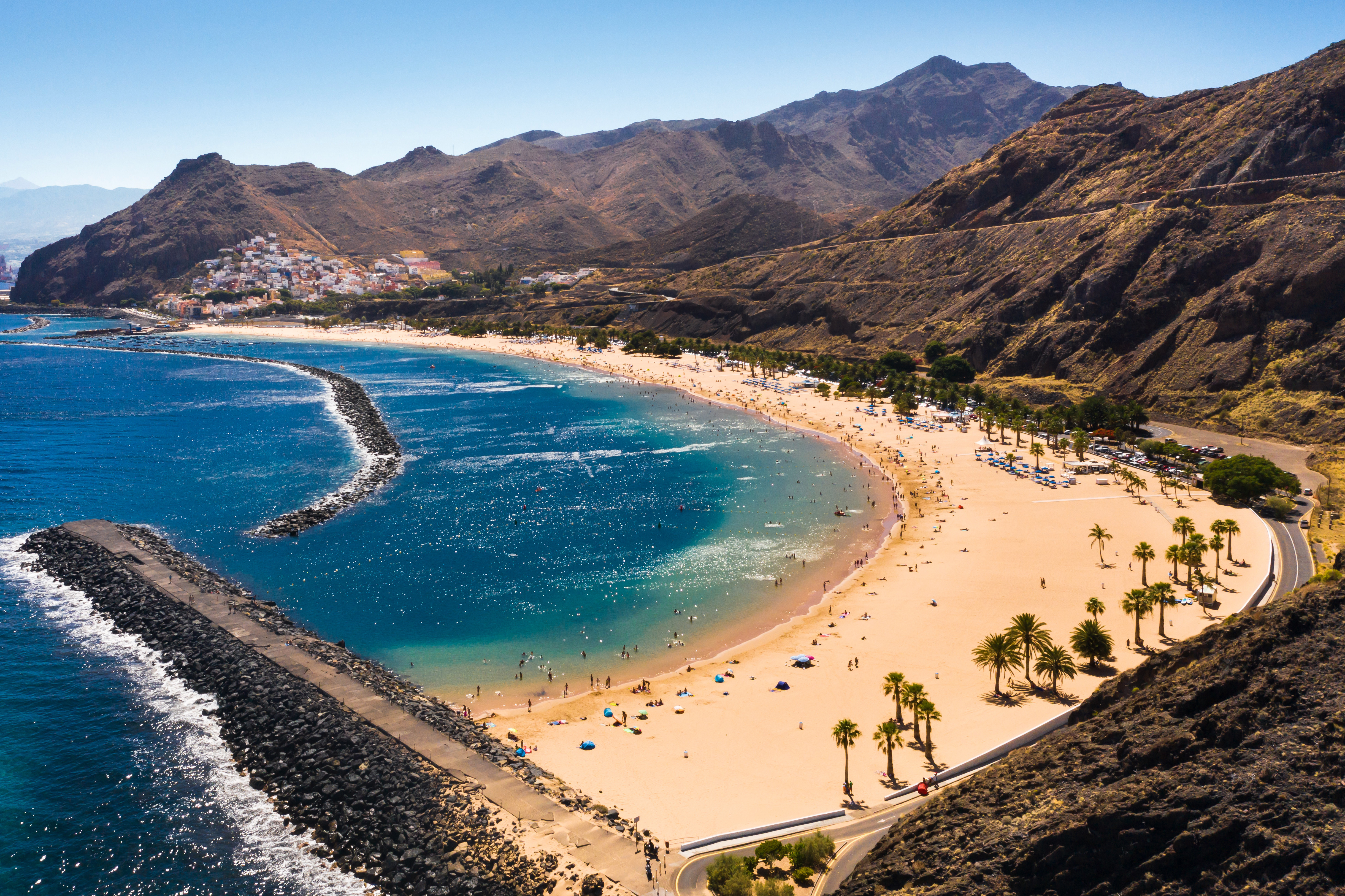 Resa till Kanarieöarna - strand med blått hav omgivet av berg och grönska