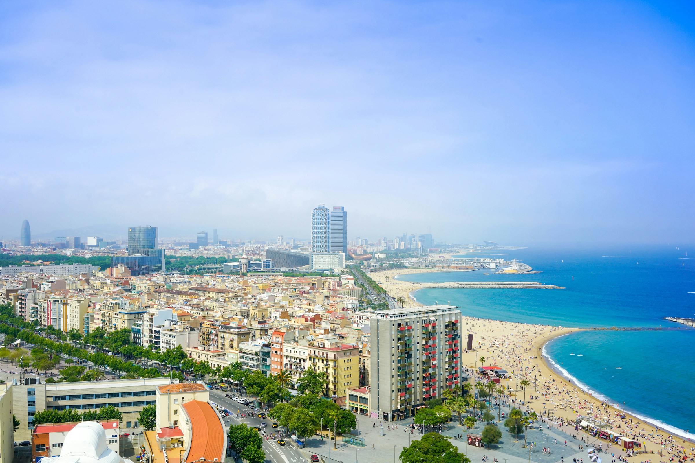 Panoramavy över strand i Barcelona med staden, byggnader och turkosblått hav i bakgrunden