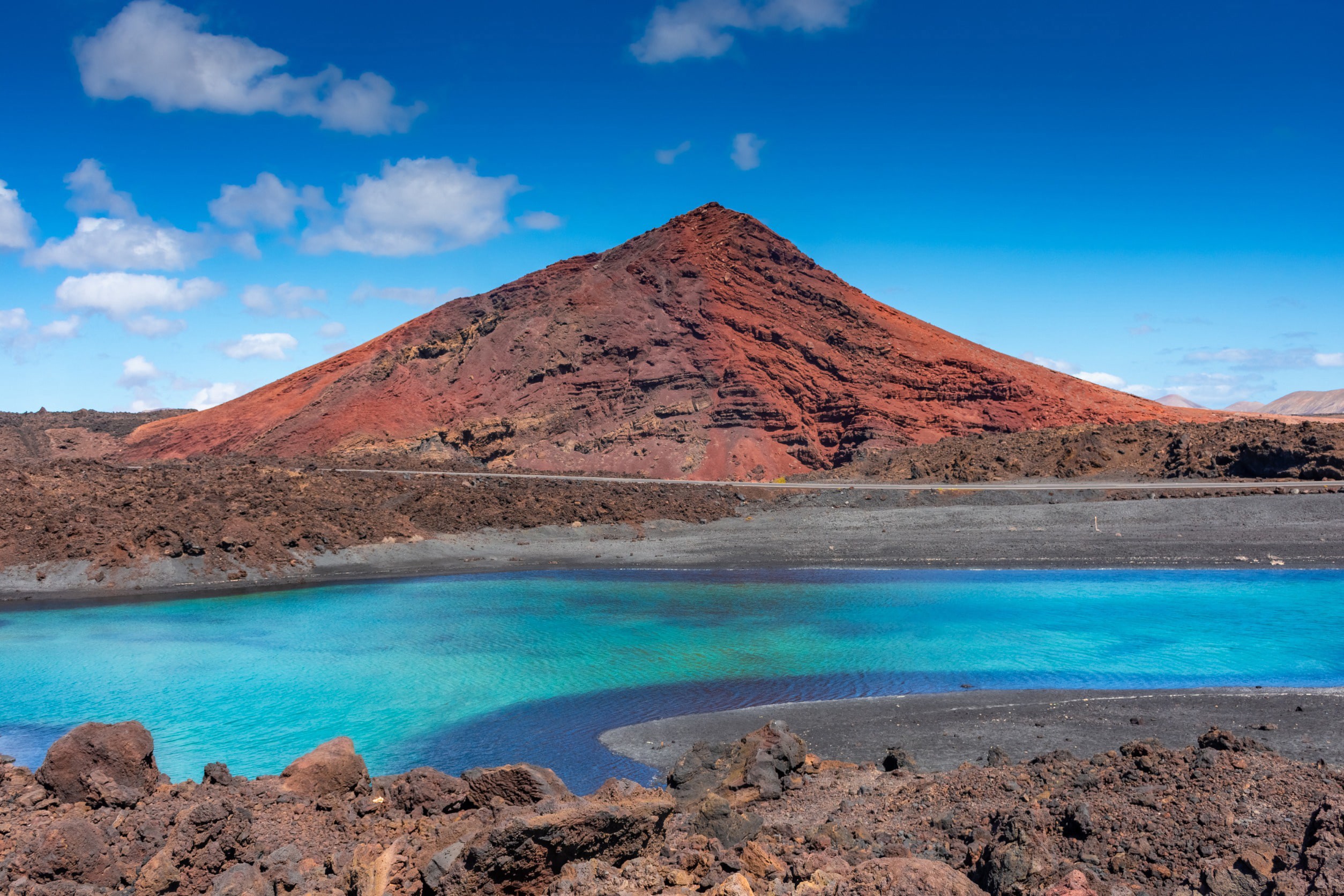 Stor vulkan på Lanzarote med turkosblått vatten framför