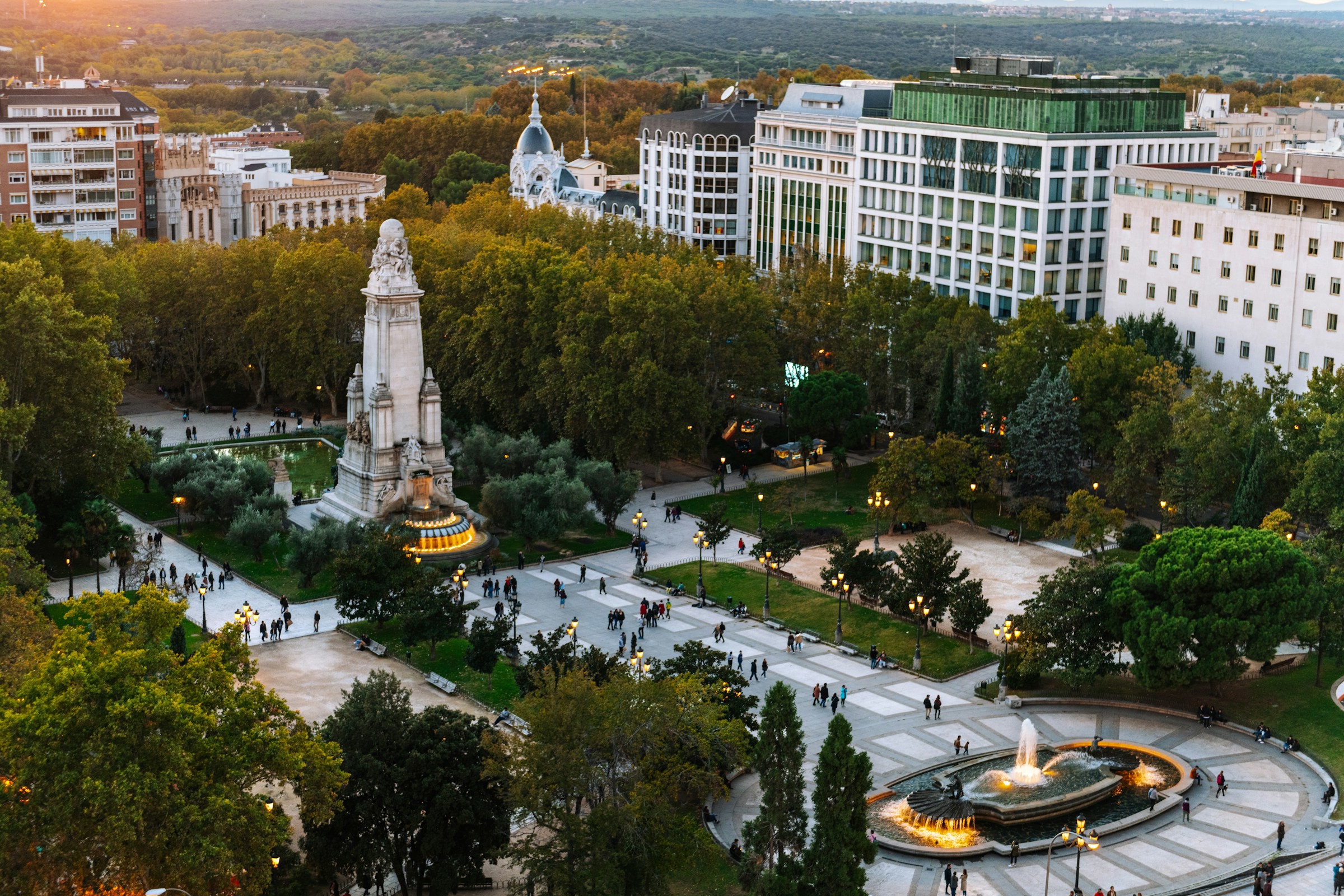 Torg och trädgård i centrala Madrid med statuer och byggnader i en solnedgång