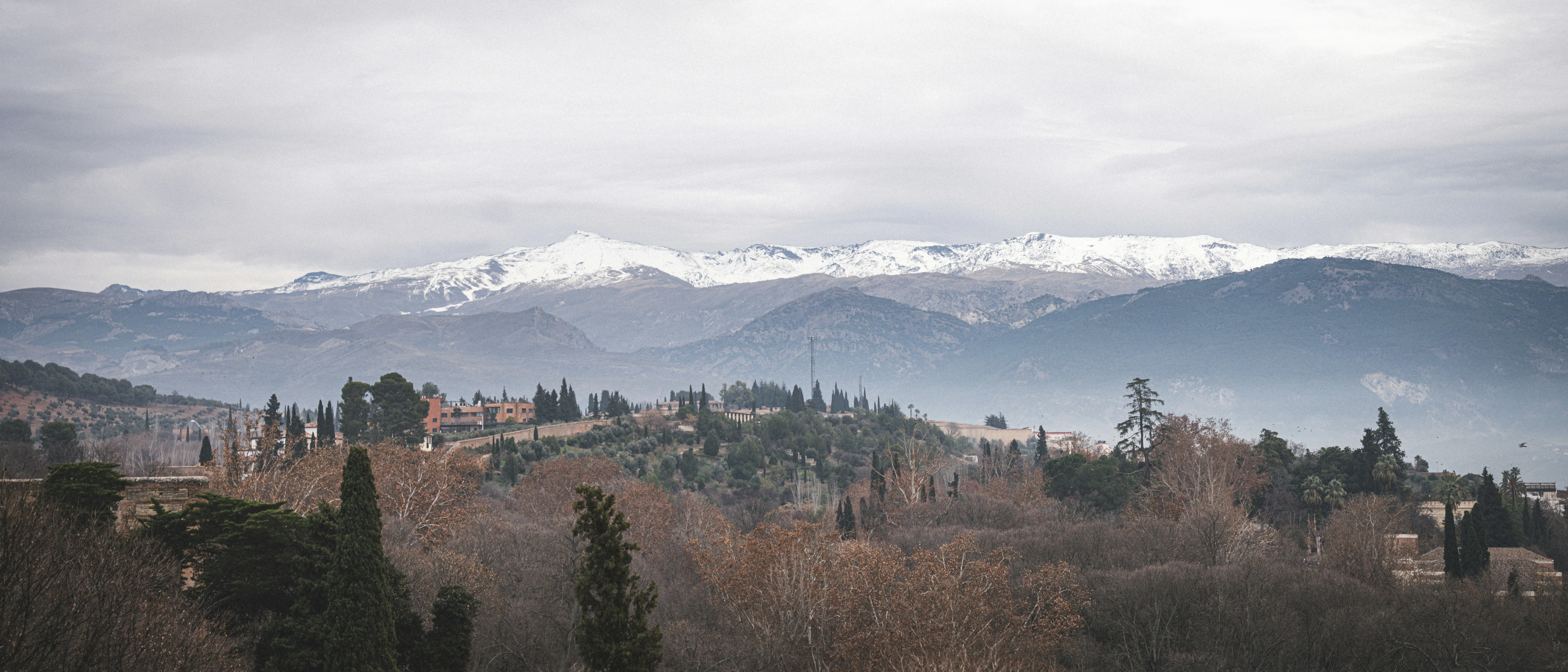 Resa till Sierra Nevada - Panoramavy över bergskedja i Spanien med snötäcka toppar och molnig himmel