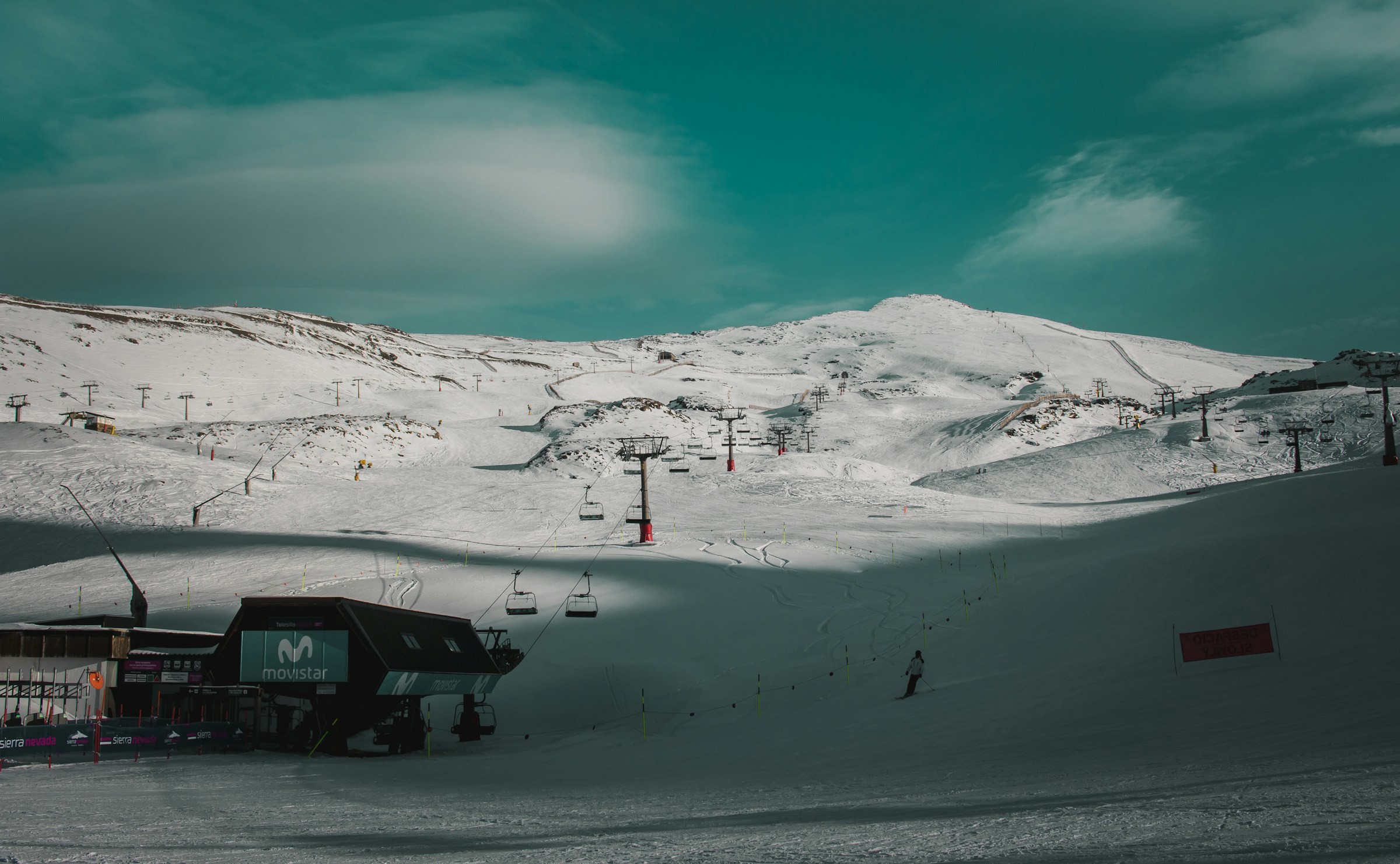 Skidbacke med skidlift leder upp mot snötäckta berg och en mörkblå himmel i Sierra Nevada