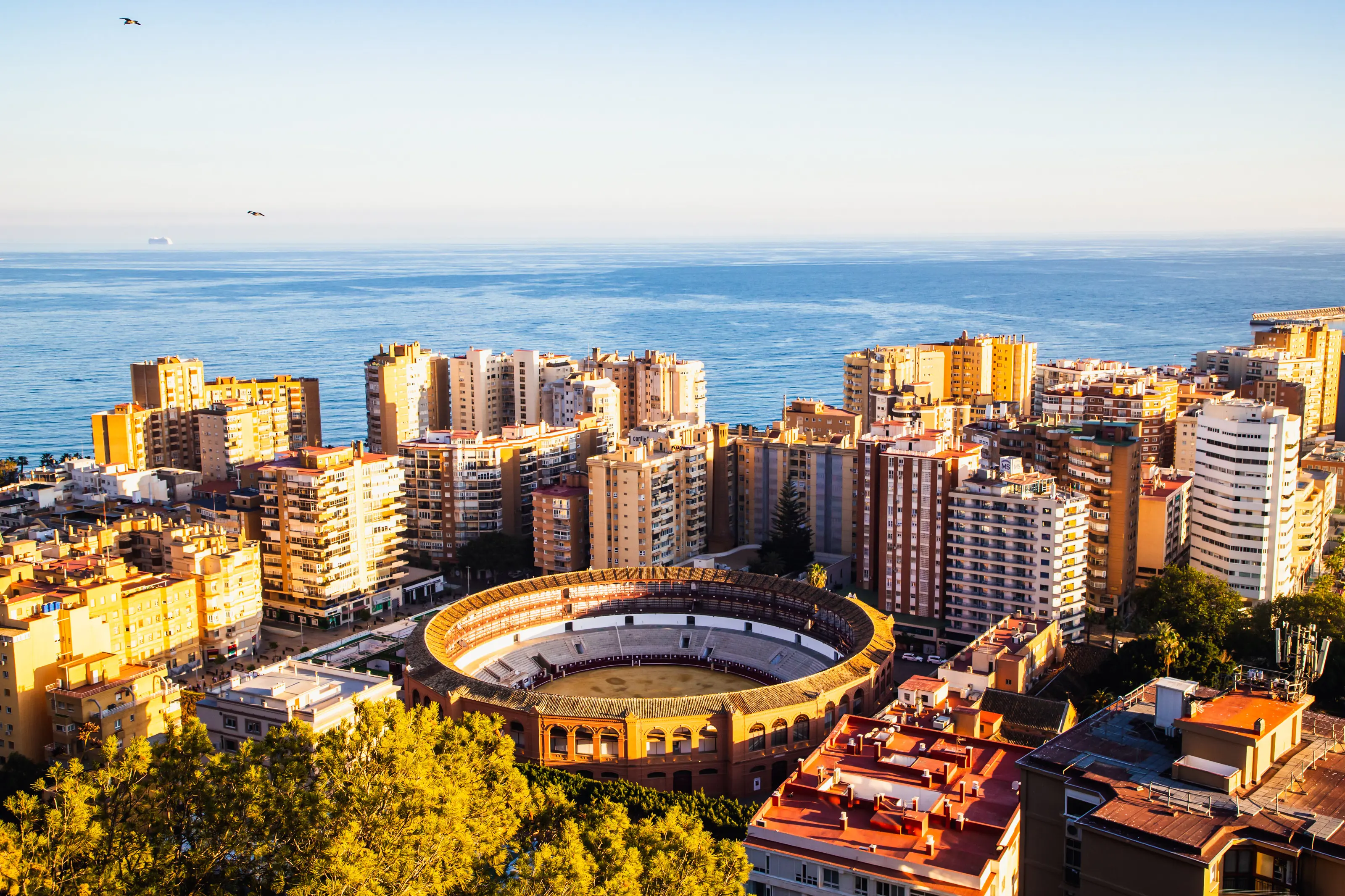 Resa till Malaga - Vy över stad med tjurfäktningsarena och havet i bakgrunden vid solnedgången.