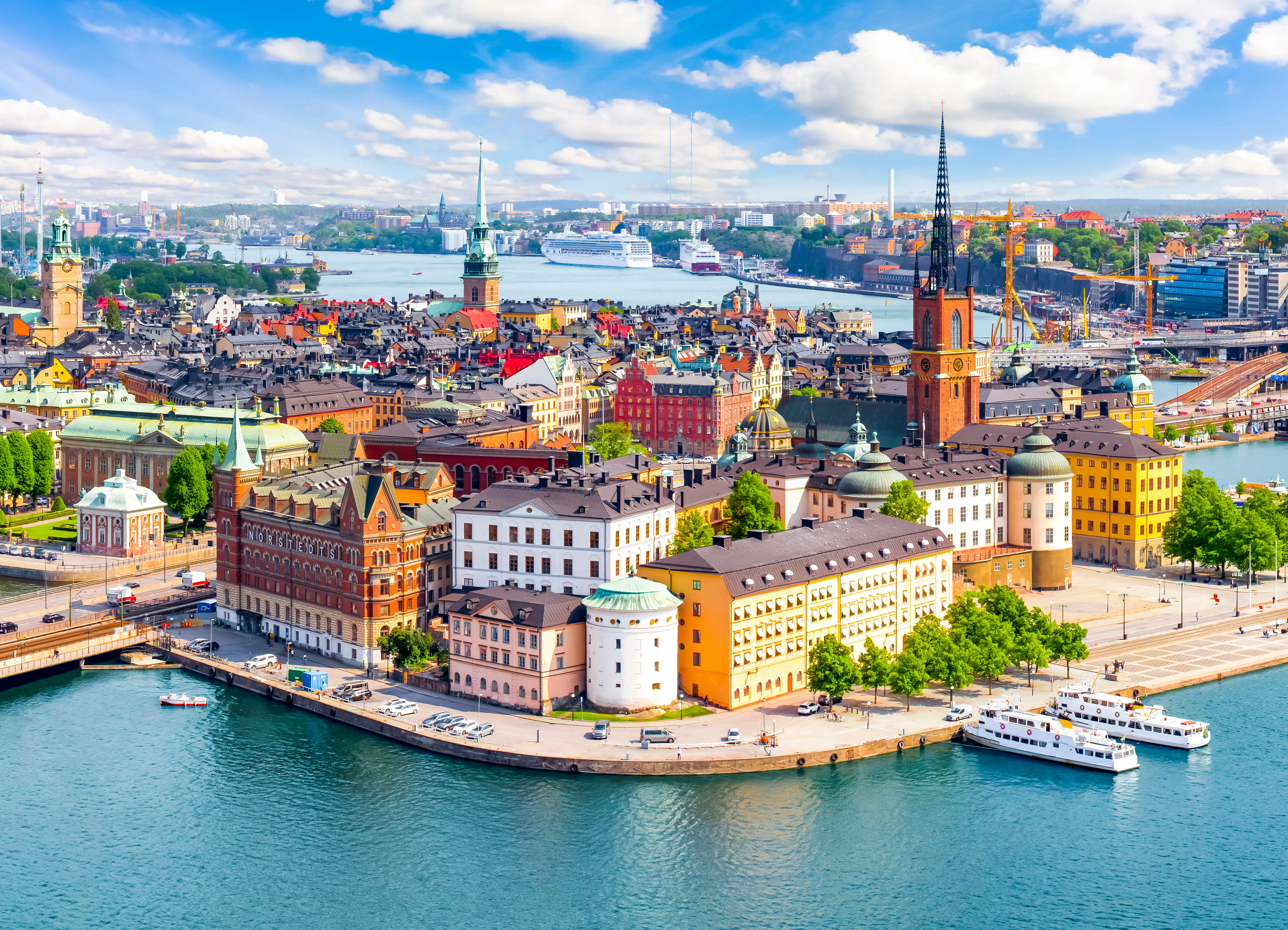 Resa till Stockholm - Panoramavy över Gamla Stan i Stockholm med färgglada byggnader och Riddarfjärden på en solig dag.