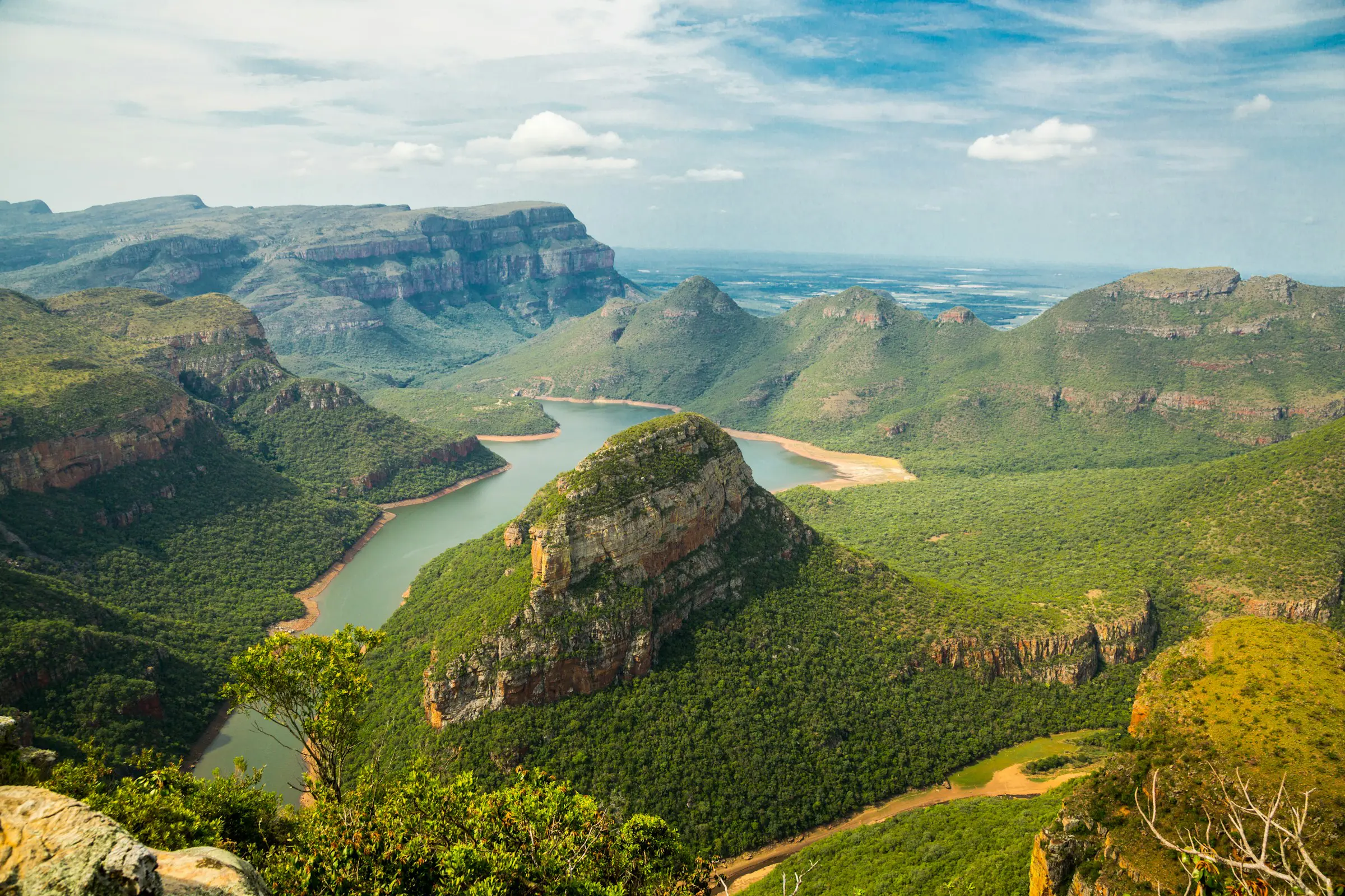 Resa till Sydafrika - Luftvy över grönskande berg och vildmark i Sydafrika med himmel och moln i bakgrunden