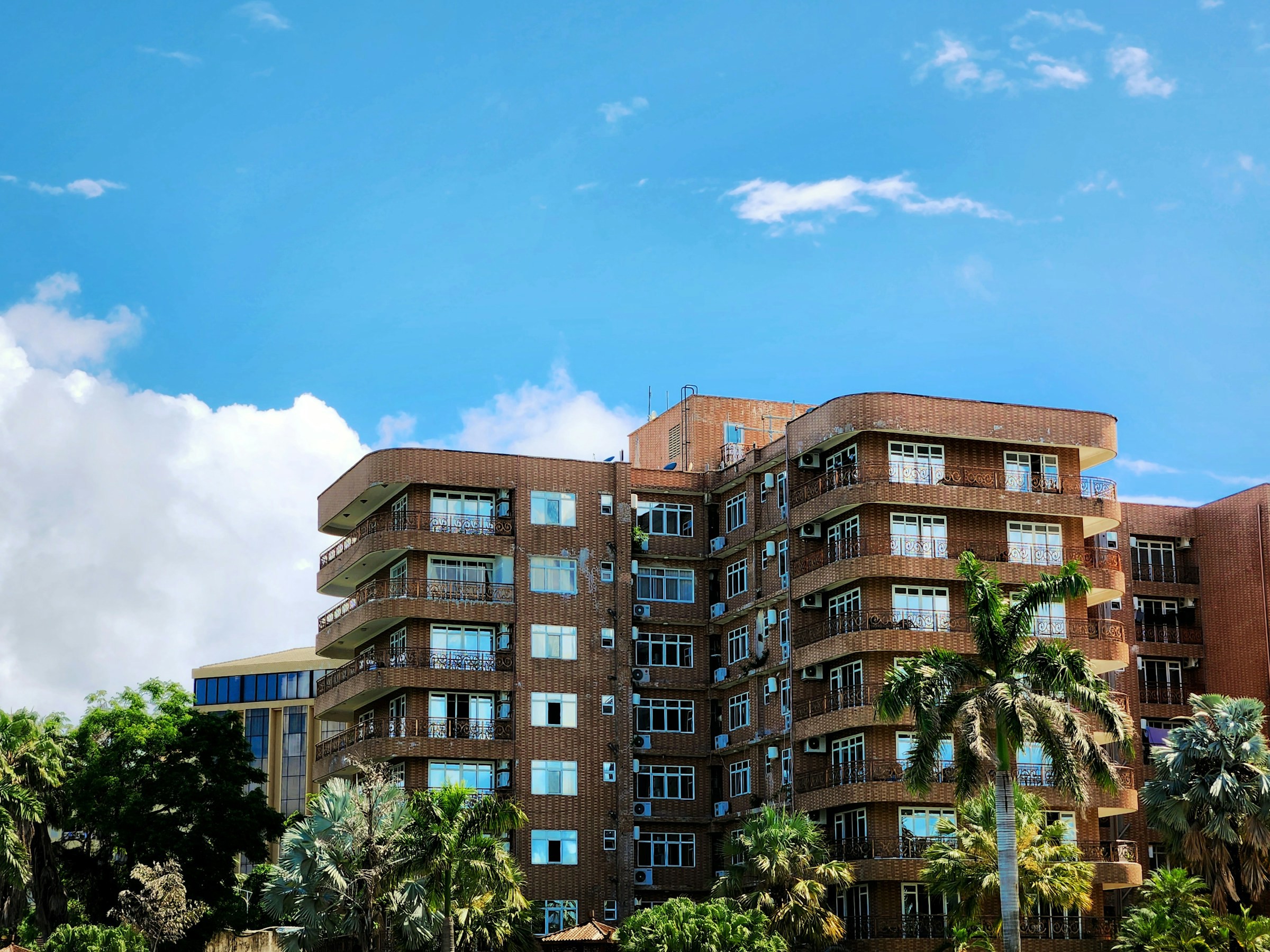 Beautiful brick building rises you among palm trees against a blue sky in Dodoma, Tanzania