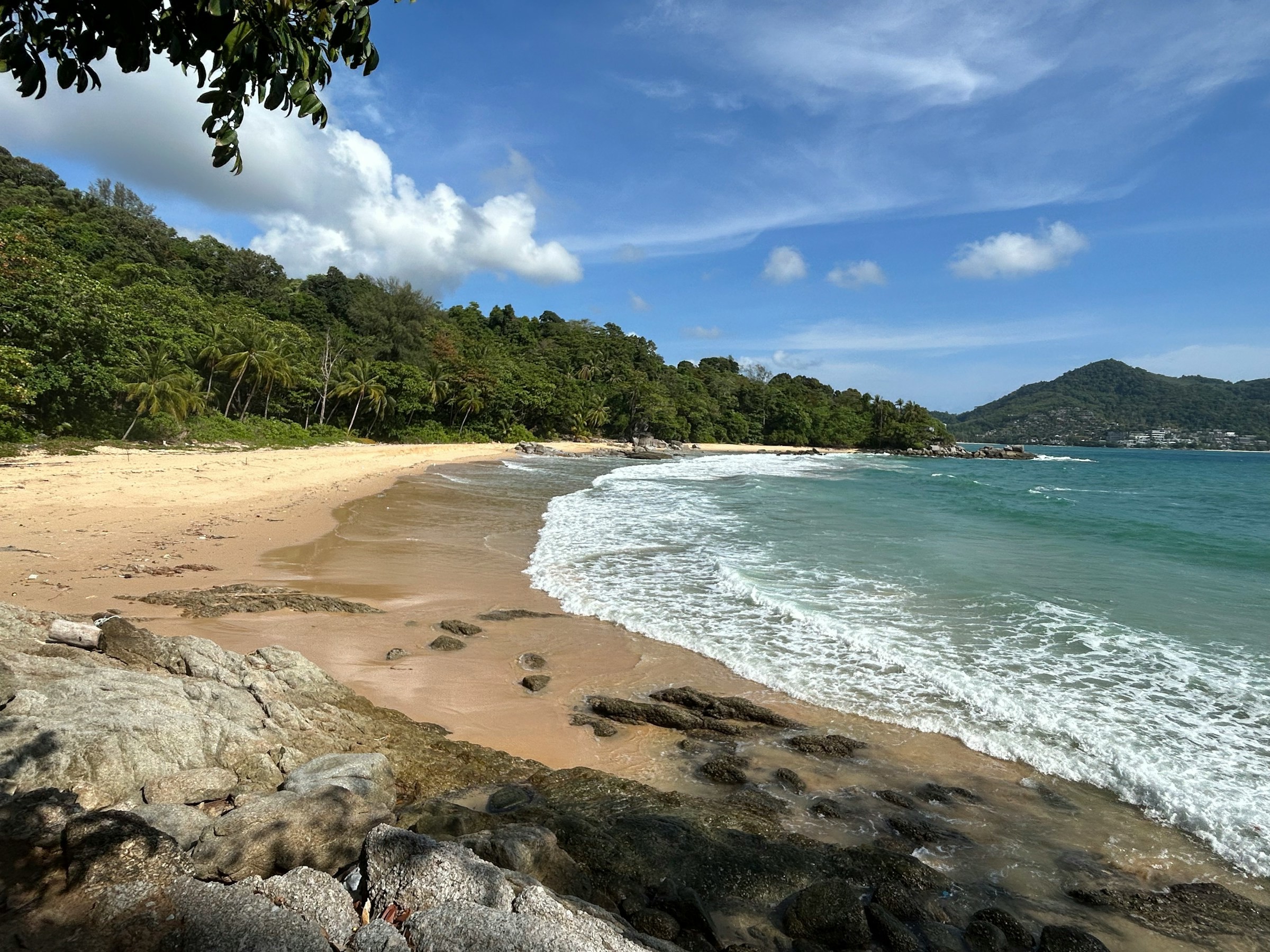 Vacker strand i Khao Lak, Thailand med blått hav med djungel som följer bort till horisonten