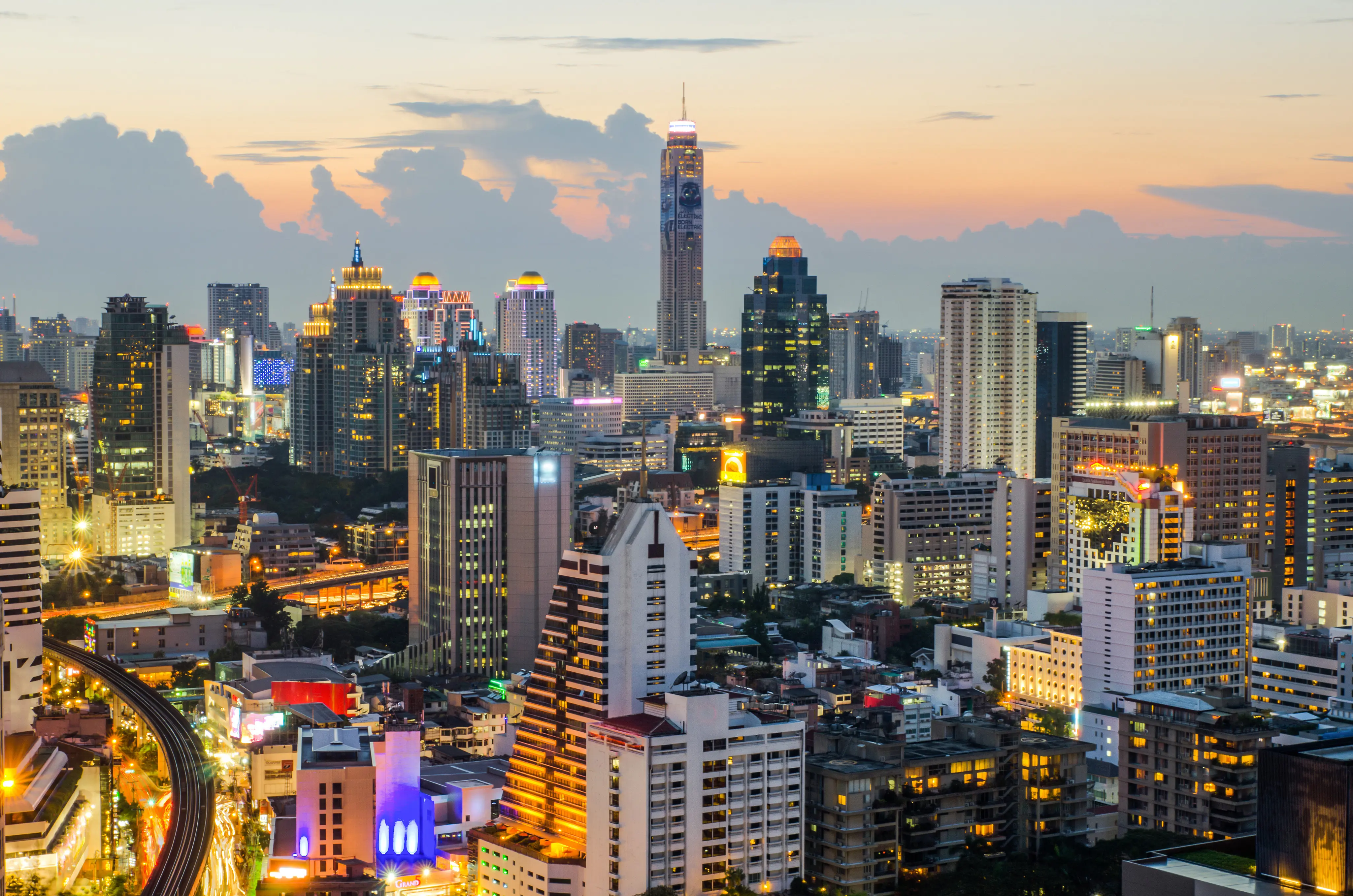 Resa till Bangkok - Skymning över lysande skyskrapor och livfulla gator i Bangkok med vacker himmel i bakgrunden