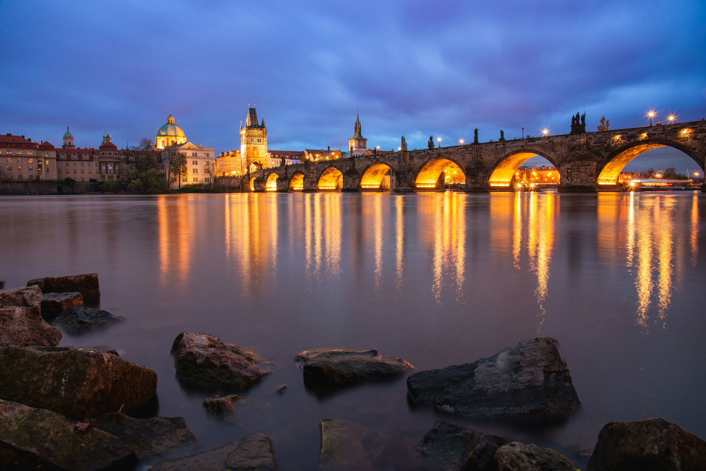 Karlsbron i Prag över en flod upplyst under nattetid