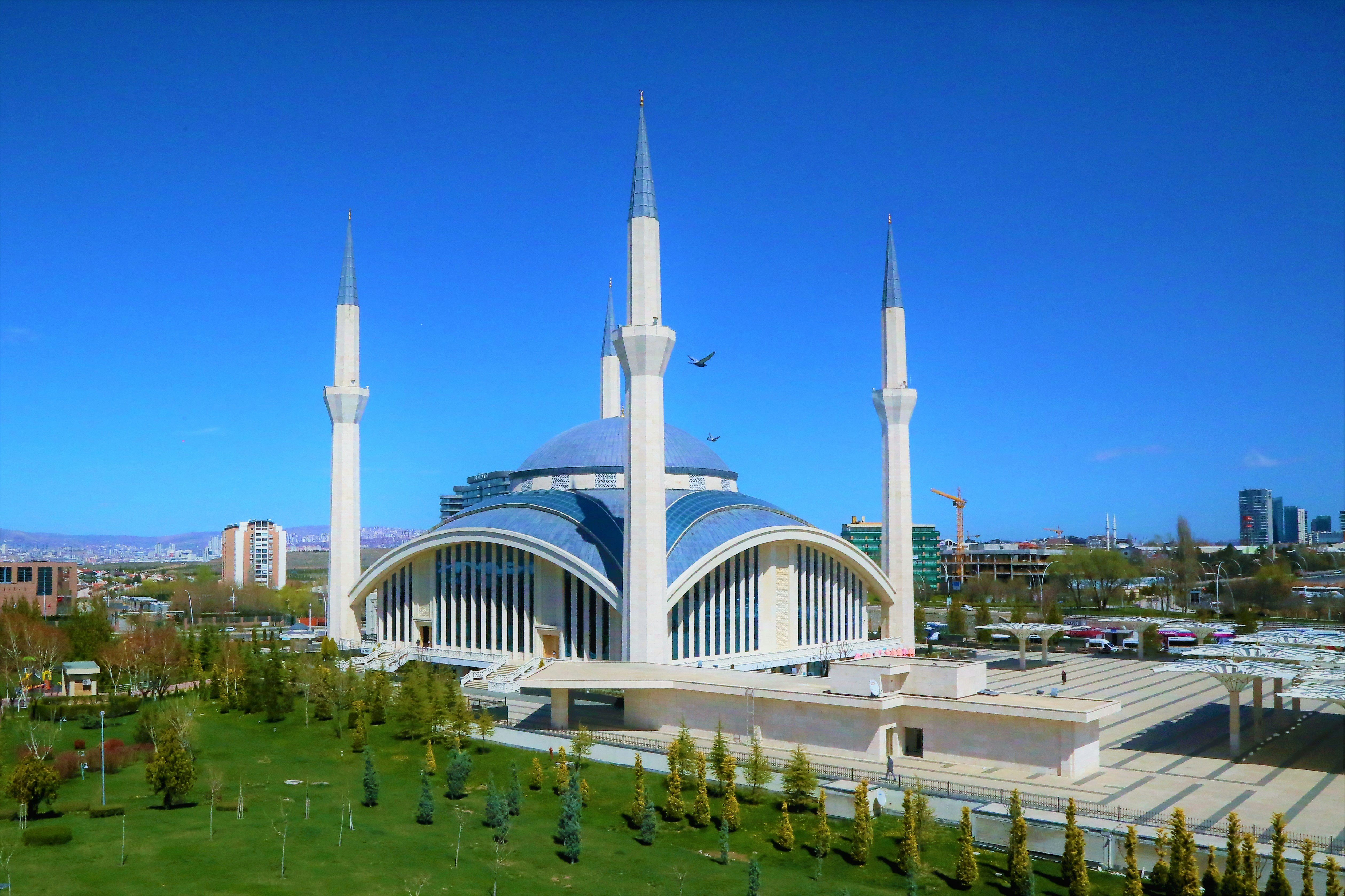 Moské med blå himmel i modernt stadslandskap, fyra minareter och kupolarkitektur i Ankara.