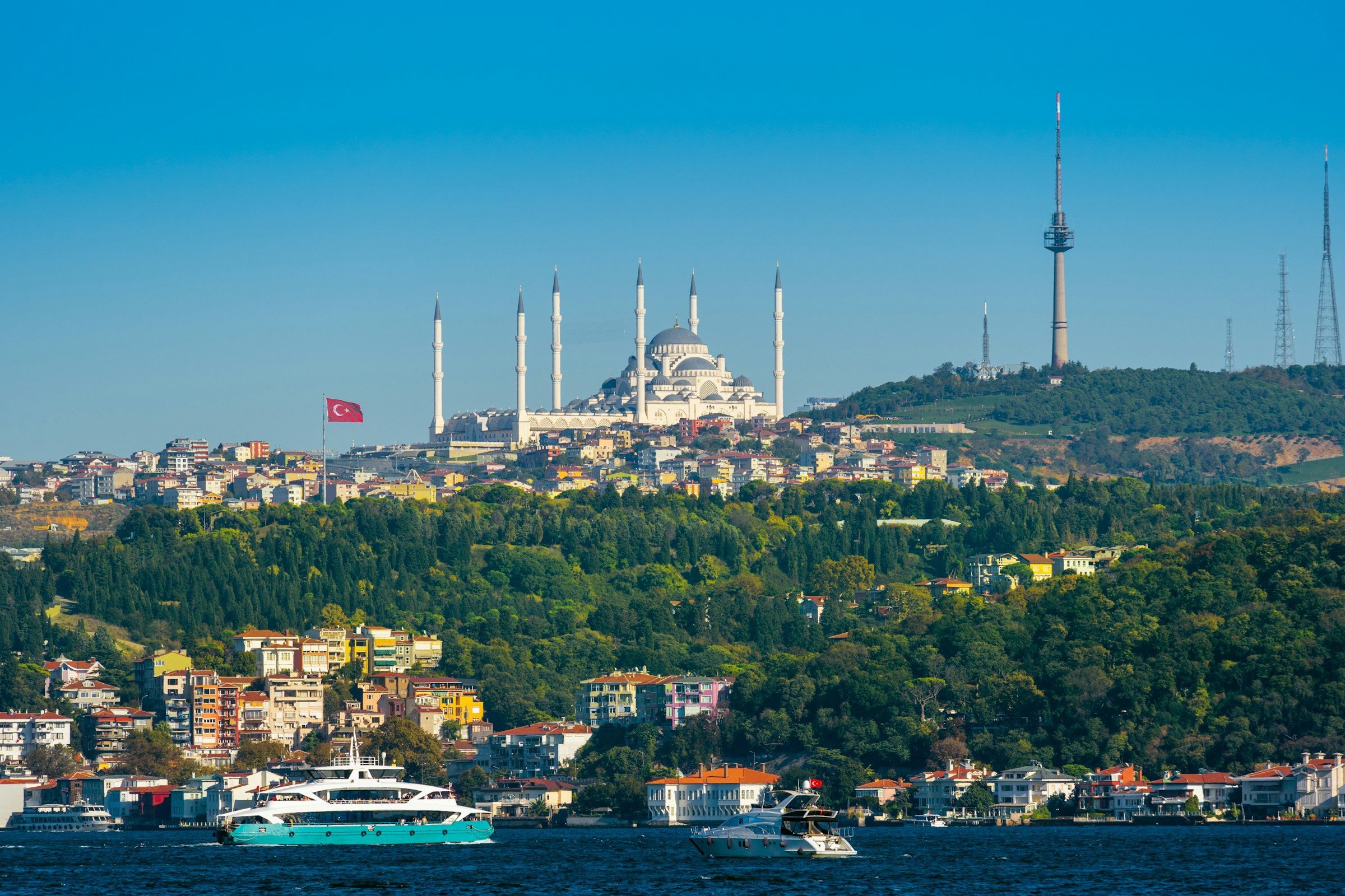 Vy över hamn och kulle i Istanbul med känd moské på toppen med skog och grönska omkring sig