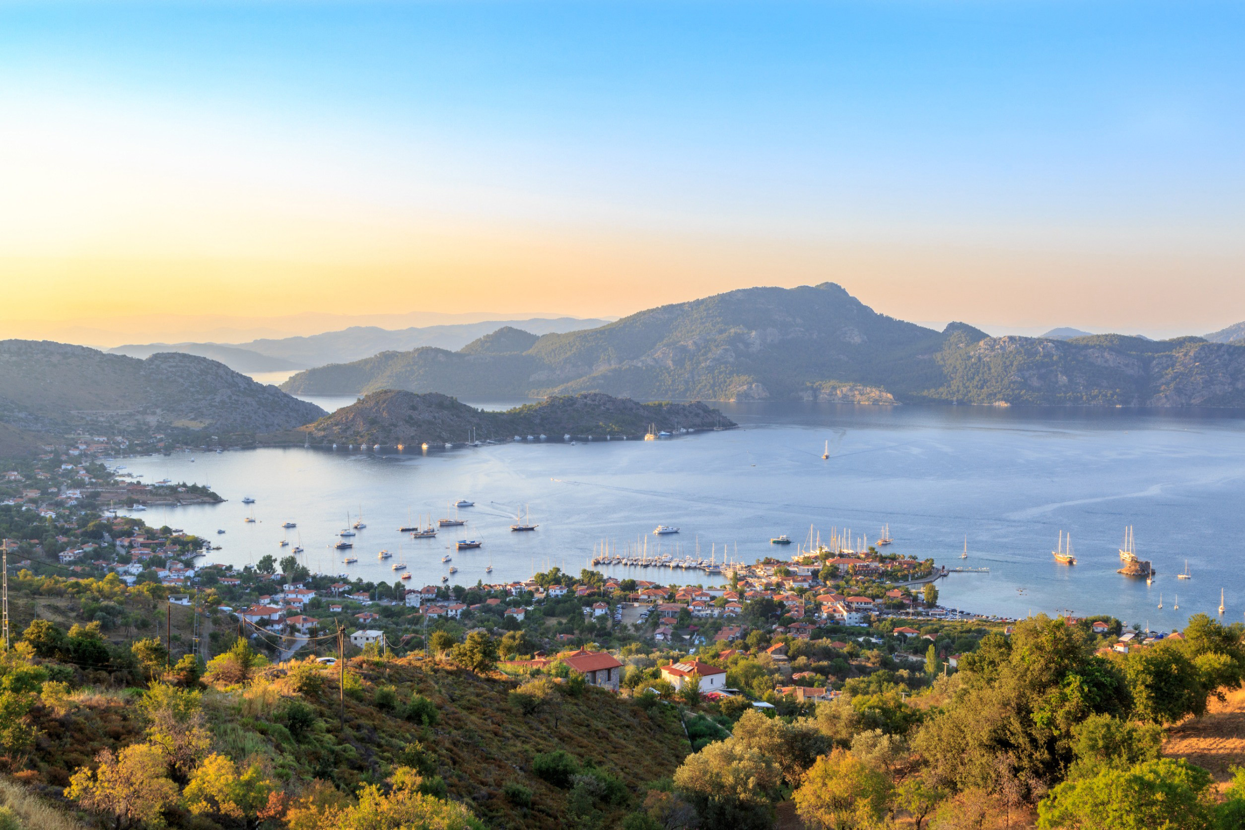 Panoramic view of Marmaris city in Turkey with lush trees, buildings, a city facing the sea and mountains in the background