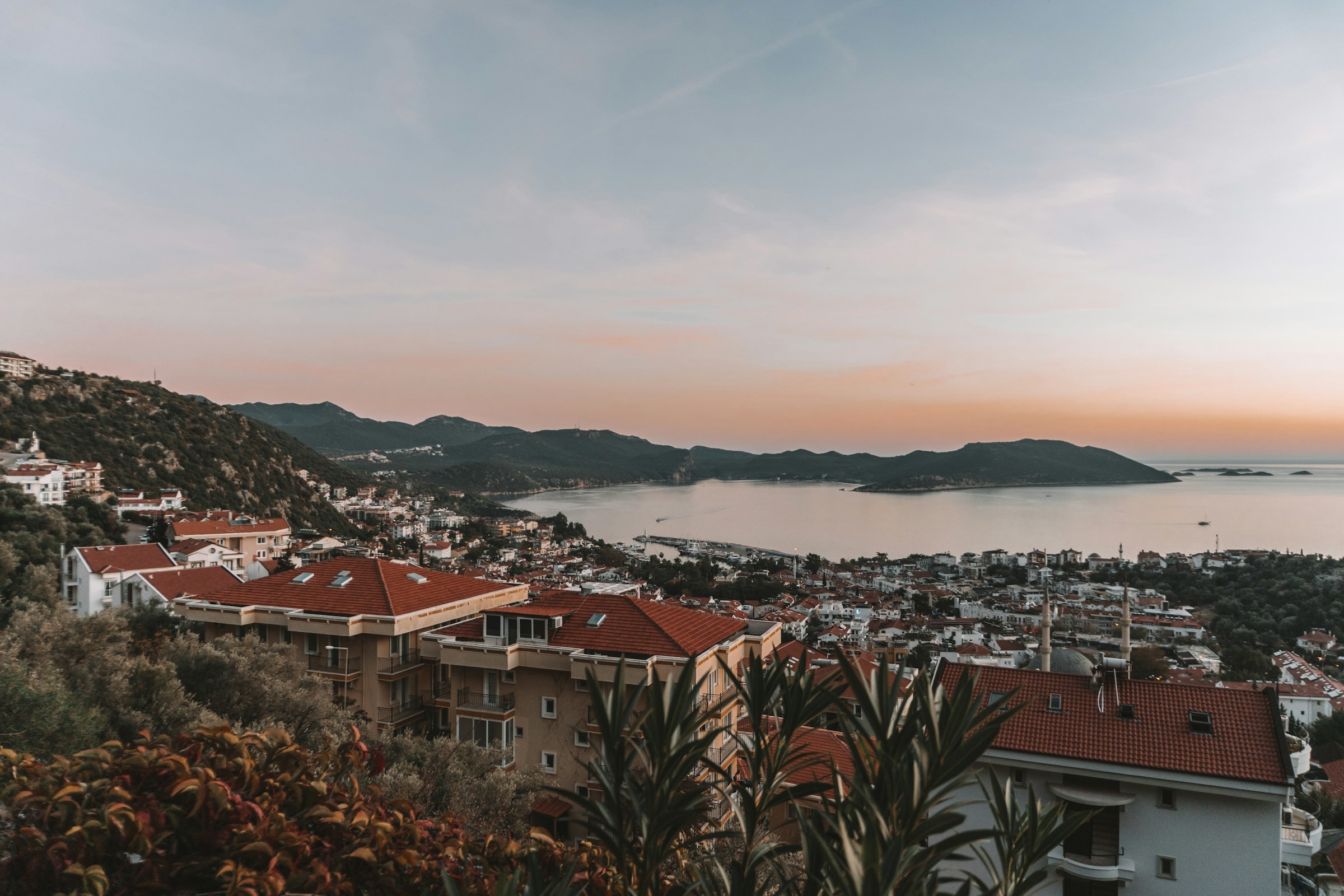 Solnedgång över stad och semesterord i Turkiet med berg och havet i bakgrunden