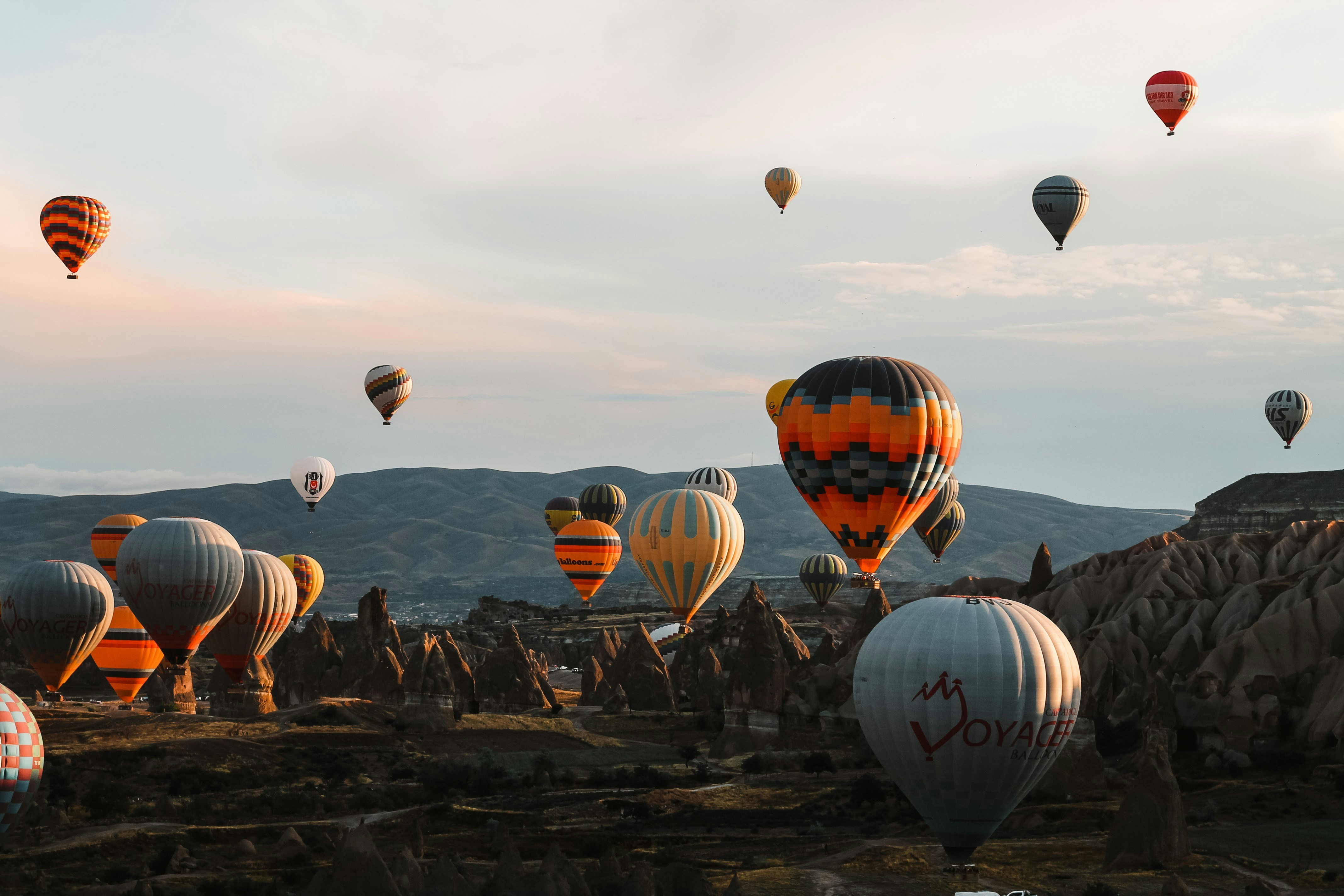 Färgglada varmluftsballonger svävar vid solnedgången över Kappadokiens unika bergslandskap i Turkiet