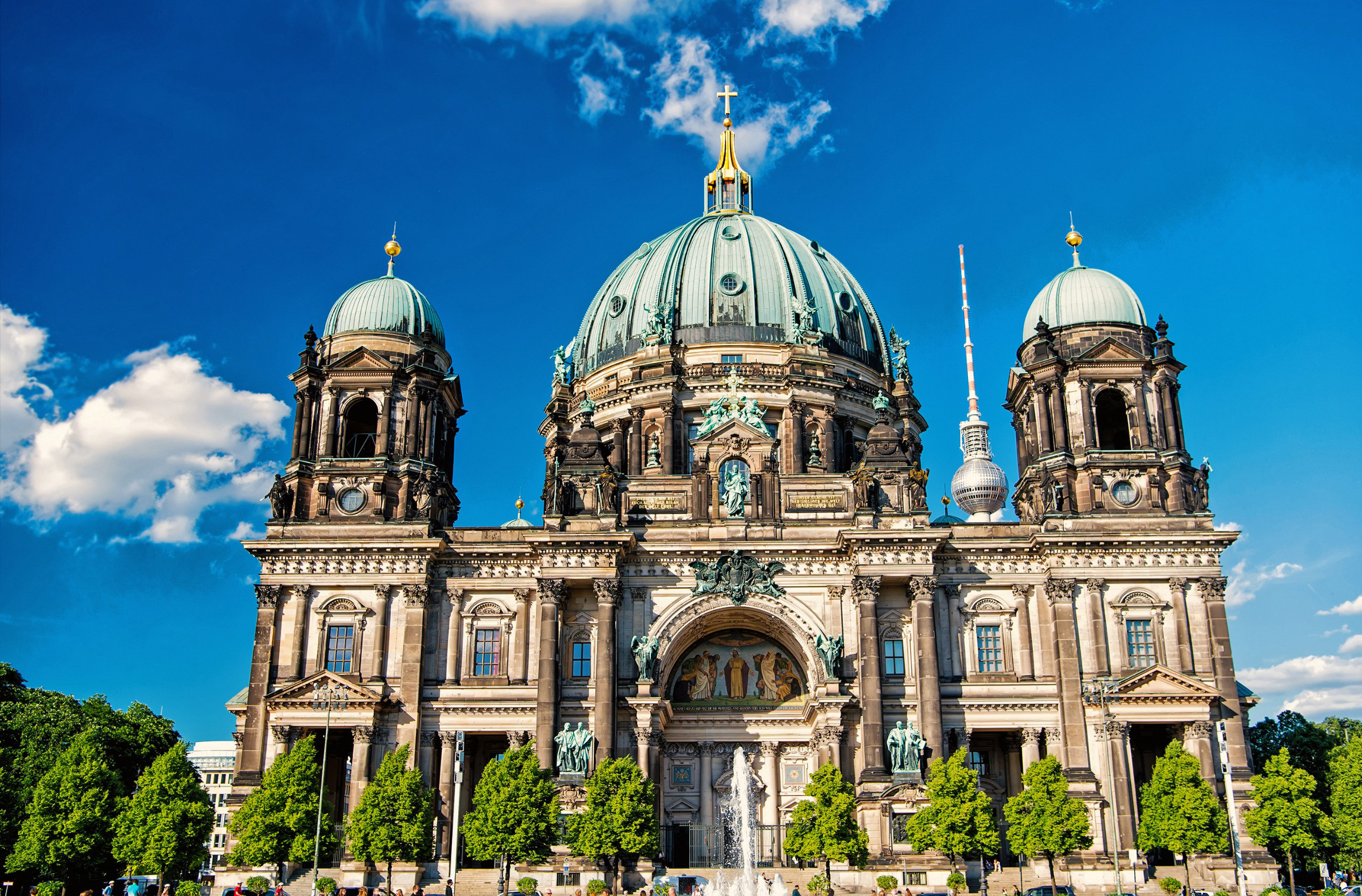 Vacker katedral med gröna buskar omkring sig reser dig upp mot en blå himmel i Berlin