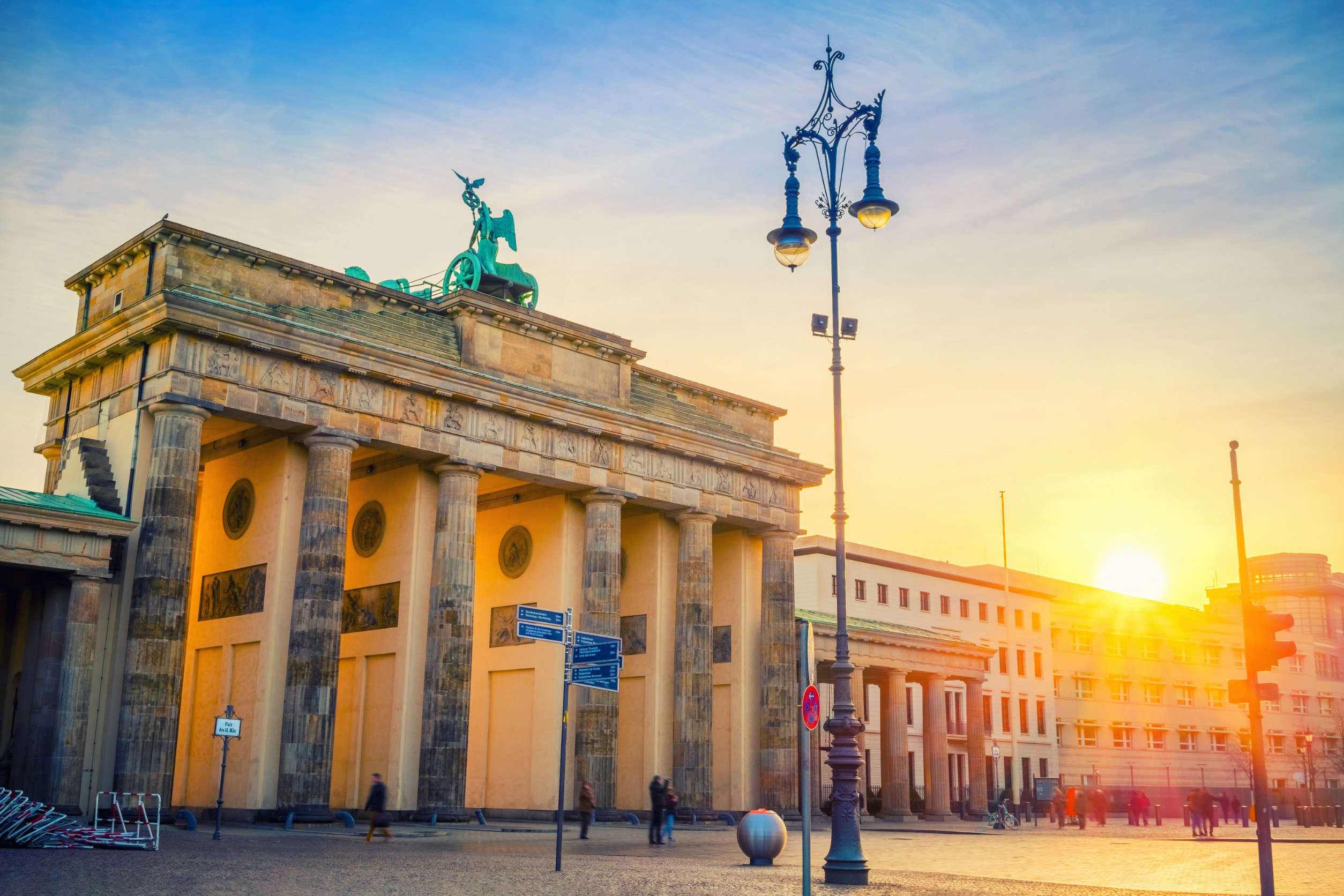 Solnedgång över ett tomt torg i Berlin med en backer ingång i sten och en staty ovanpå