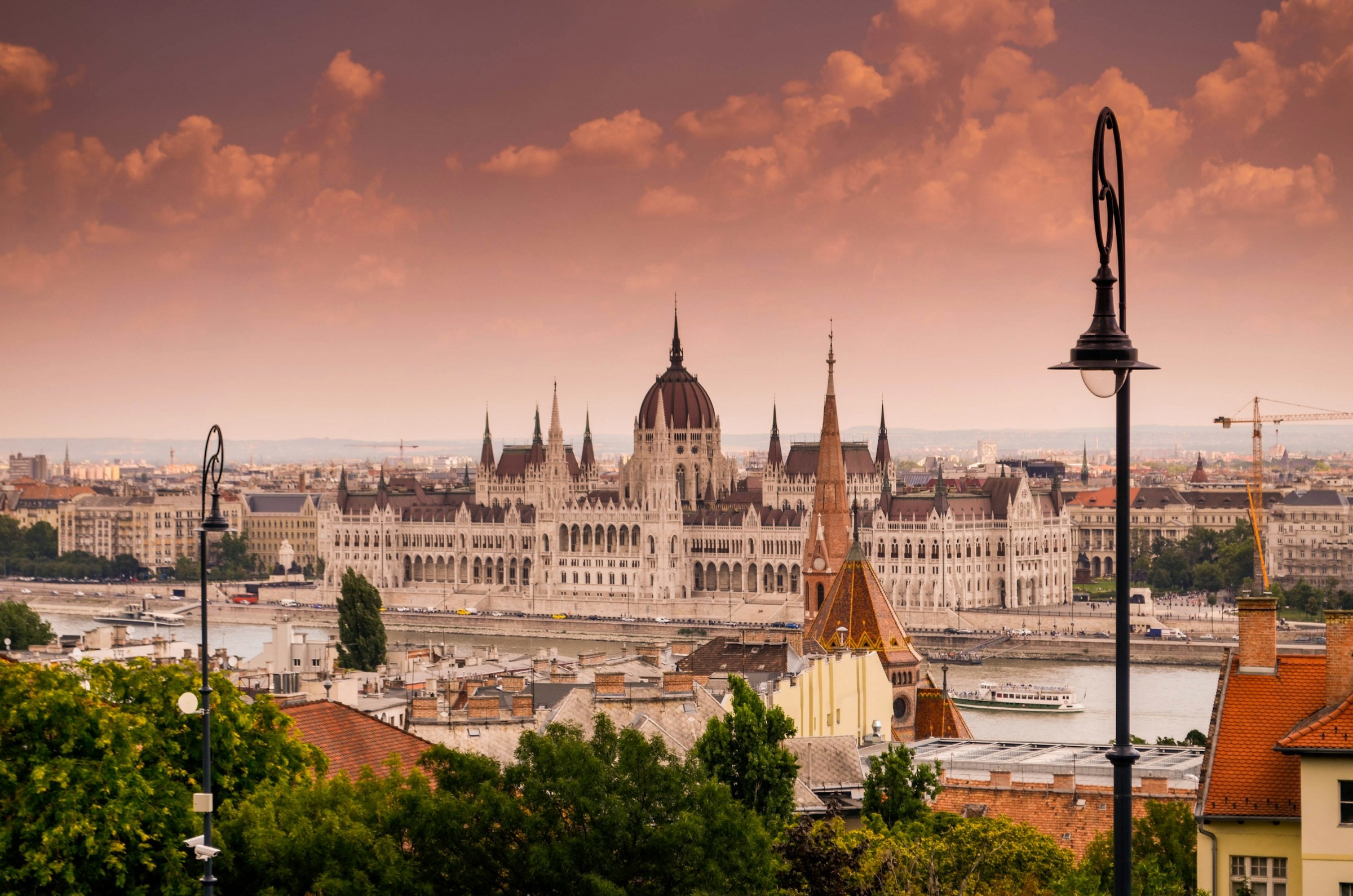 Solnedgång över palatset i Budapest, Ungern med stadsmiljö runtomkring och vacker röd himmel i bakgrunden