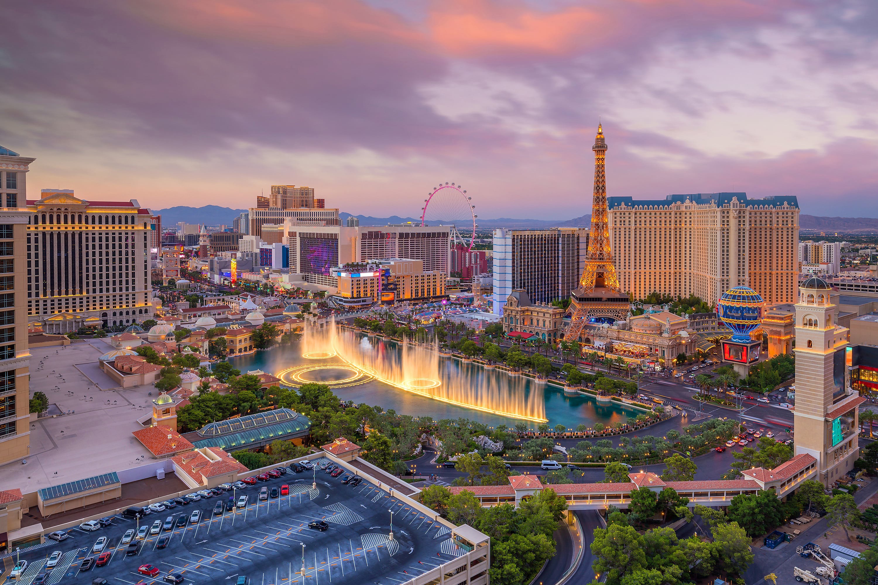 Fågelvy på vackert stort hotell i Las Vegas med lysande fontän och lilla himmel under skymning