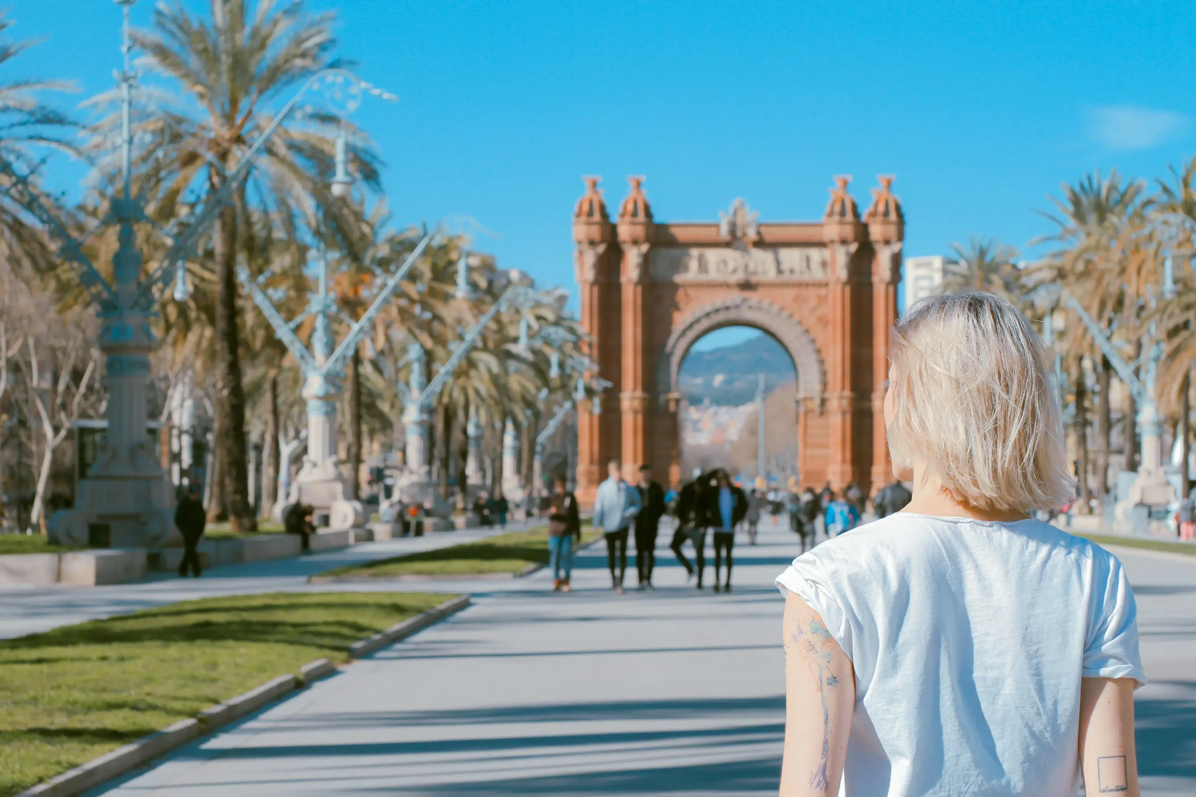 Triumfbågen i Barcelona med promenerande människor och klarblå himmel.