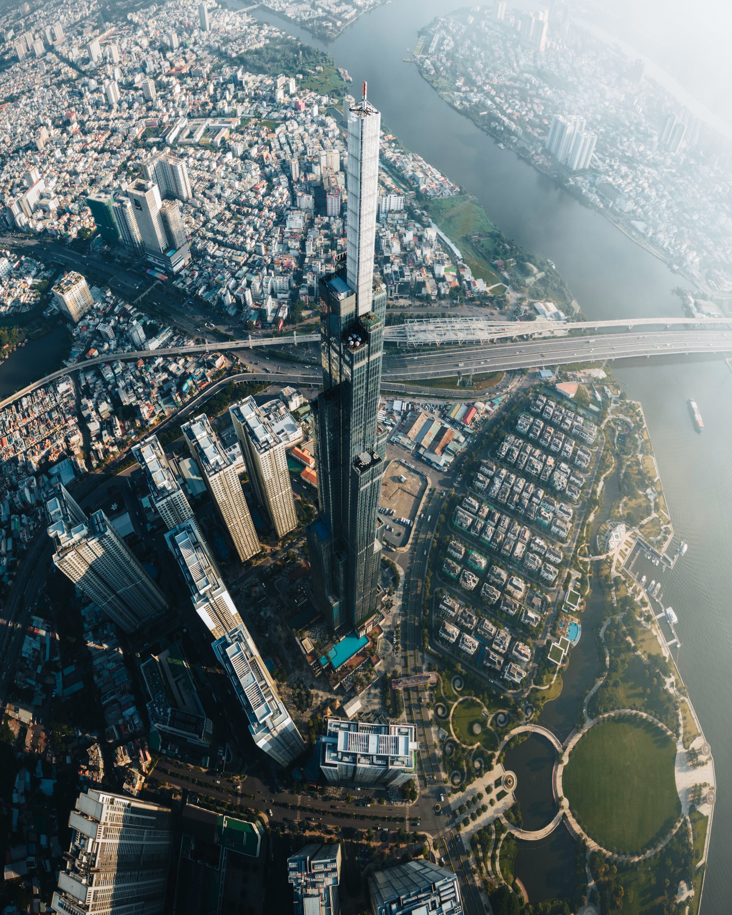 Aerial view of Ho Chi Minh City by the water with tall skyscrapers and bridges, in an urban landscape.